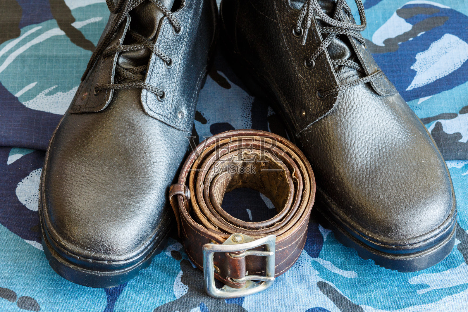 军靴和蓝色迷彩服军带。士兵的工装裤。照片摄影图片