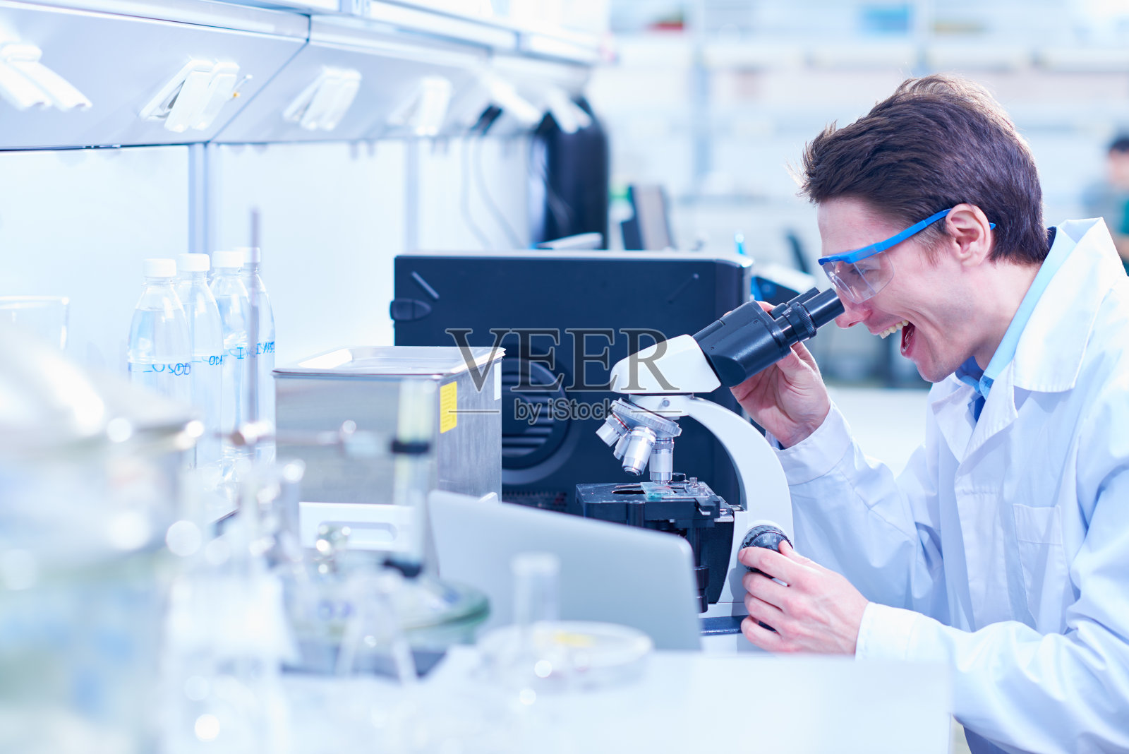 兴奋的科学家在显微镜下观察样品照片摄影图片