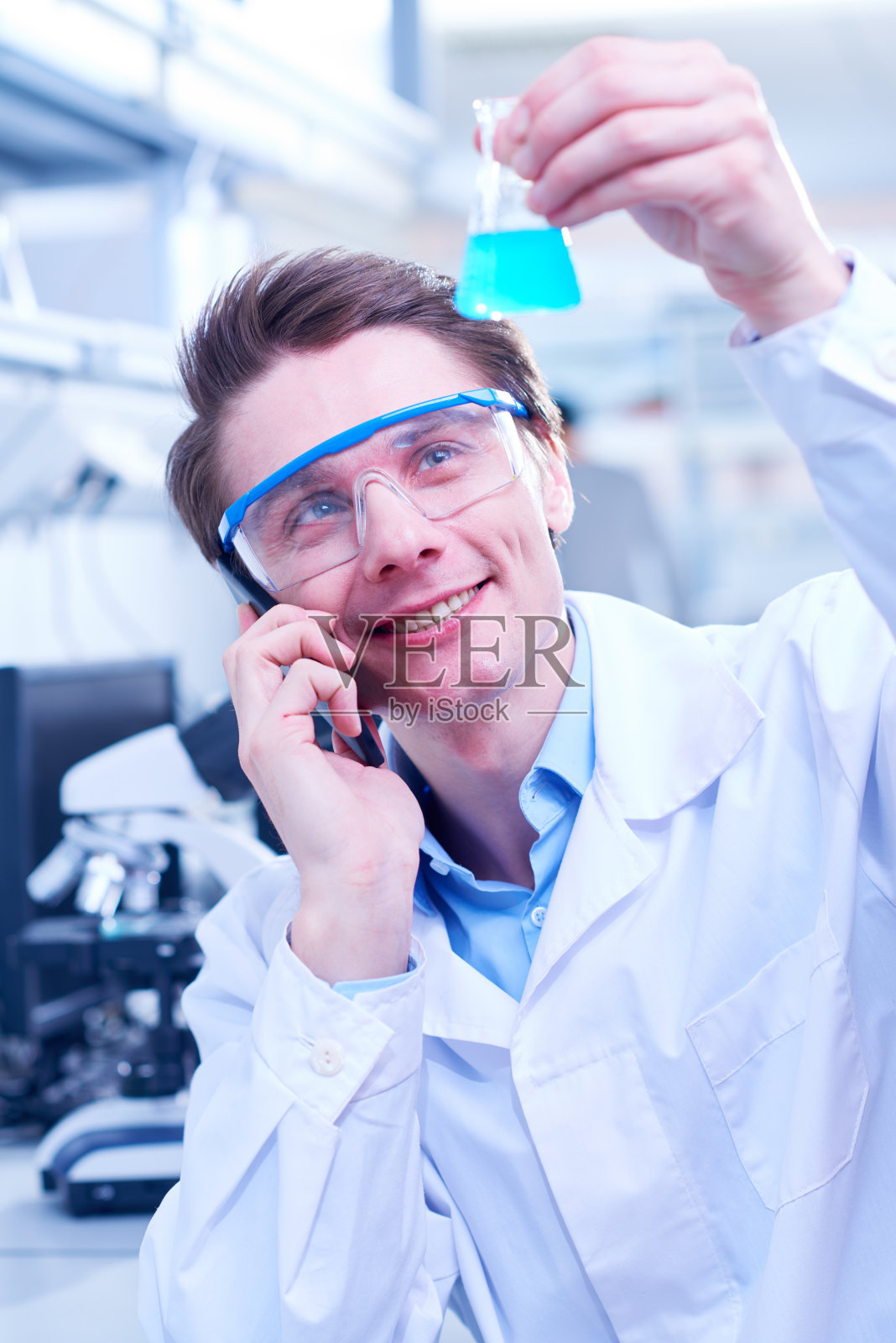 拿着装有化学品的烧瓶的男子正在打电话照片摄影图片