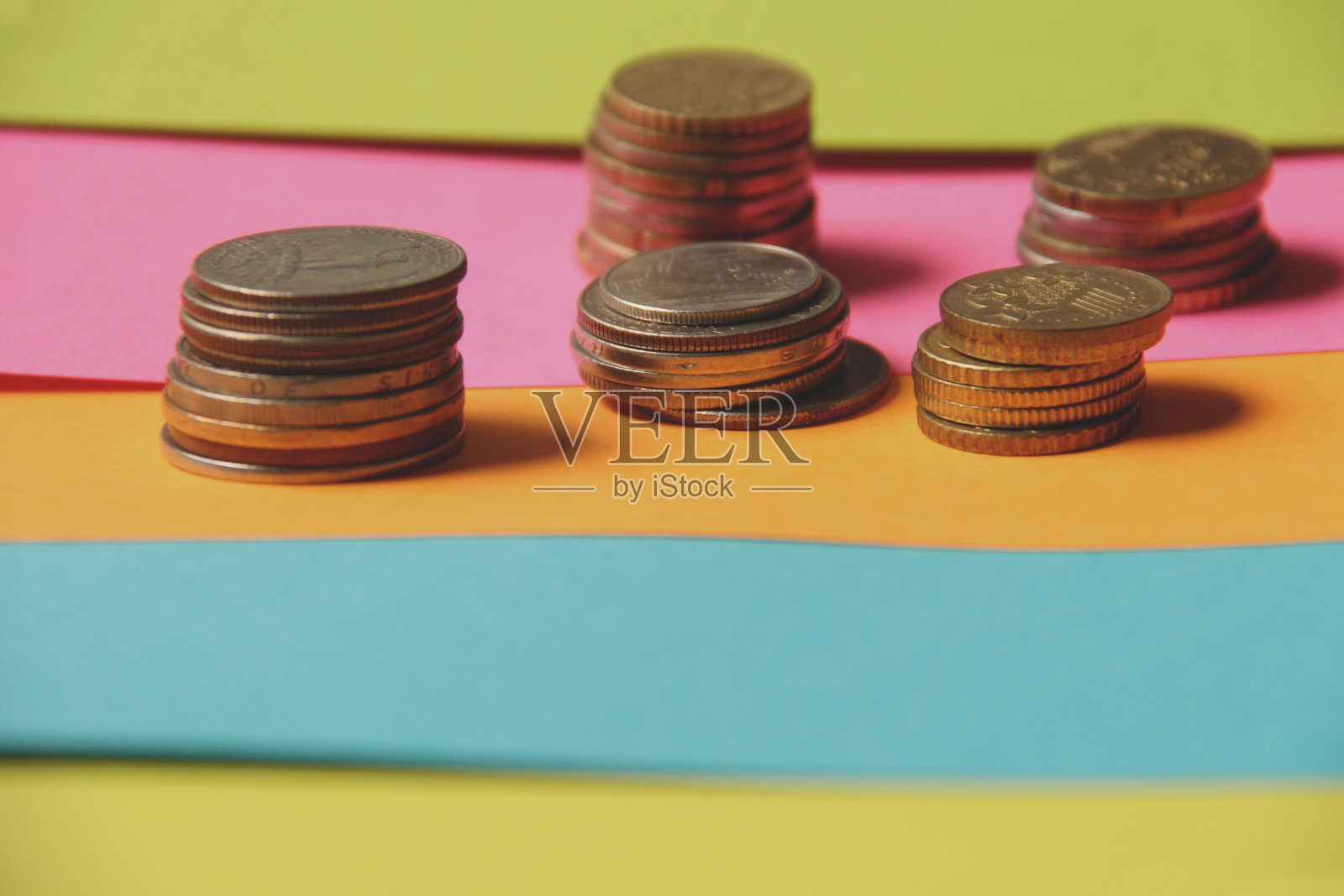 不同国家的硬币和硬币叠在彩色的纸上。这张照片显示了不同范围和品种的经济成功。照片摄影图片