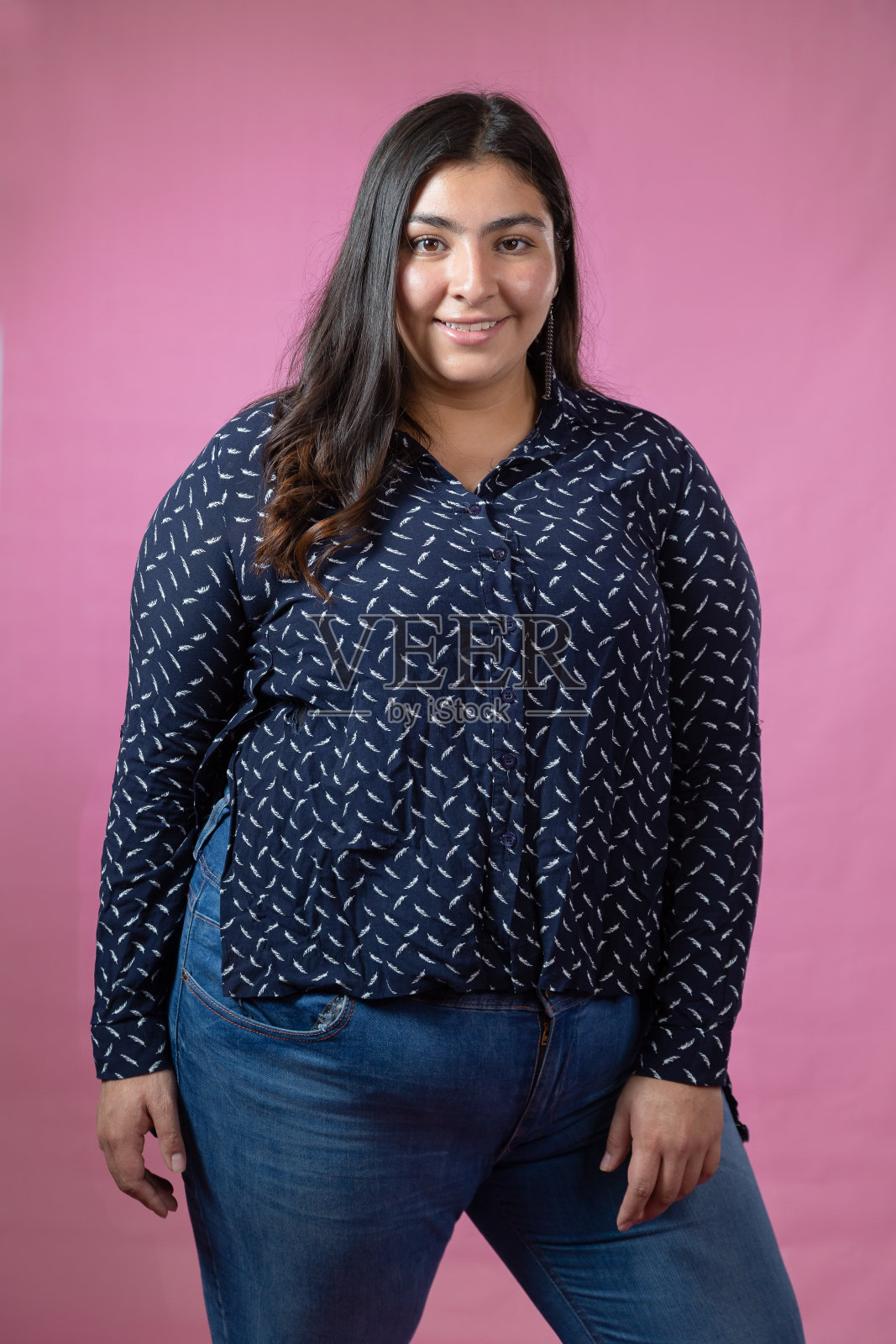 一个胖乎乎的女人站在画室里，粉红色的背景照片摄影图片