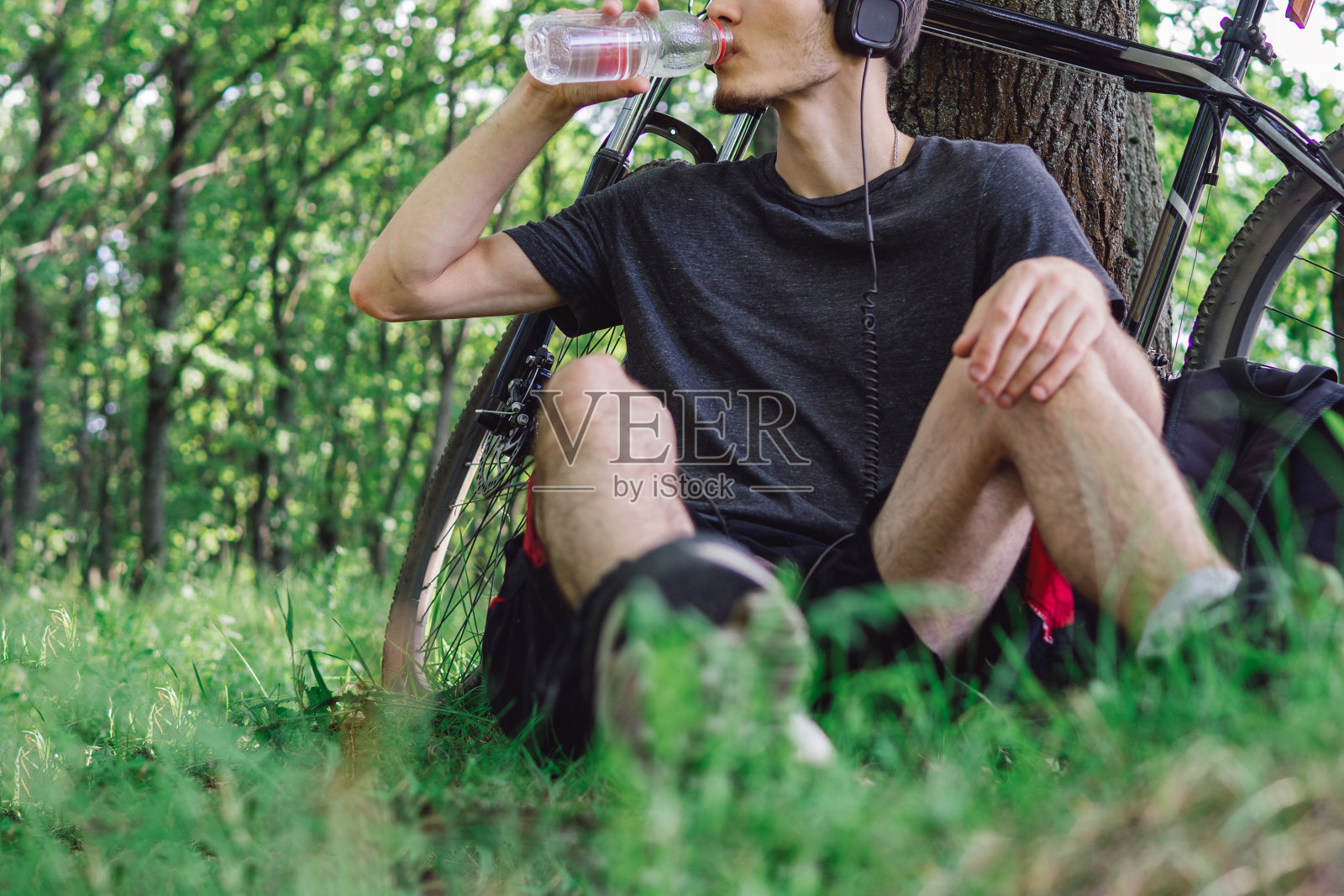 年轻的男性骑自行车喝水。在公园和森林里骑车。健康积极的生活方式照片摄影图片