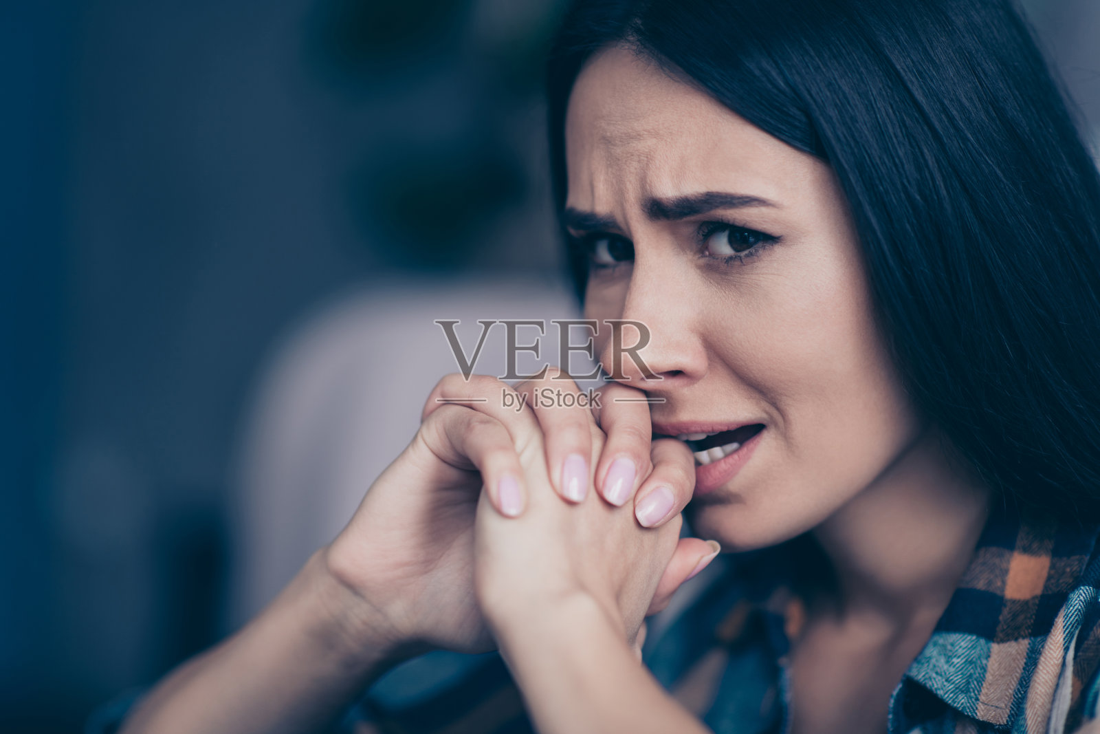 失望的女子特写侧脸，双手合十，紧咬牙关，身穿格子衬衫，舒适地坐在客厅里照片摄影图片