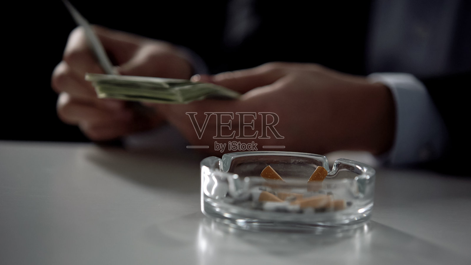 烟灰缸，后台数钱的人，非法交易照片摄影图片