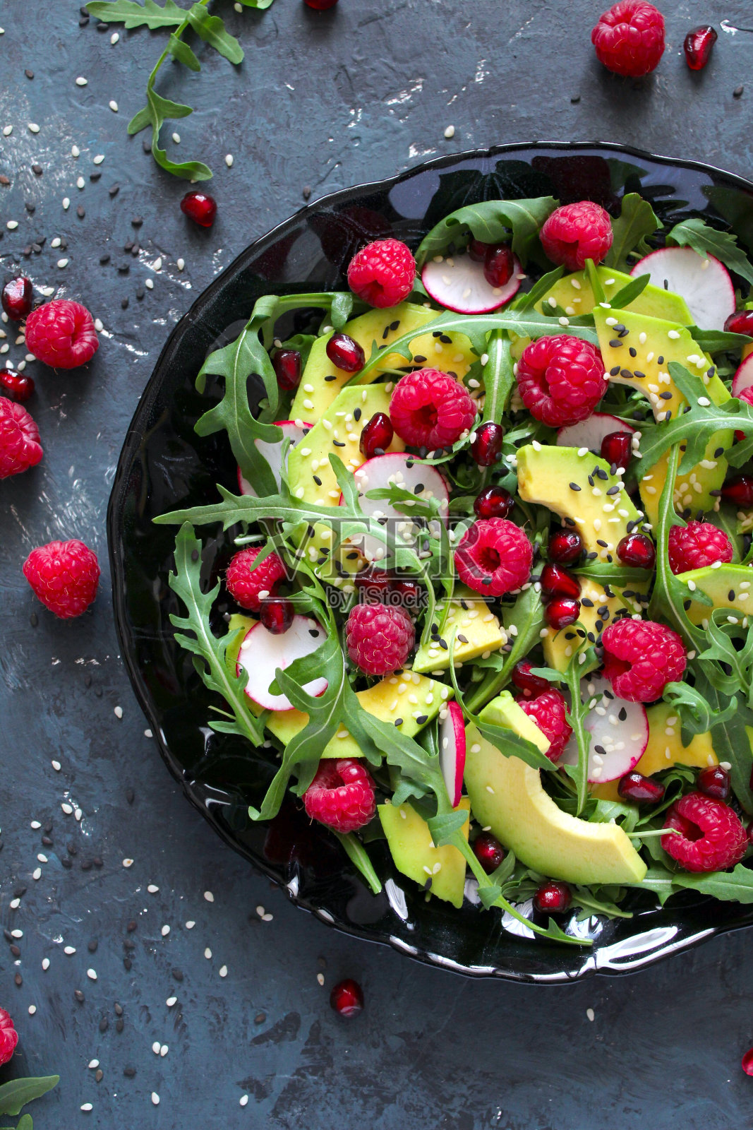 牛油果沙拉配上覆盆子，石榴，芝麻菜和芝麻。照片摄影图片