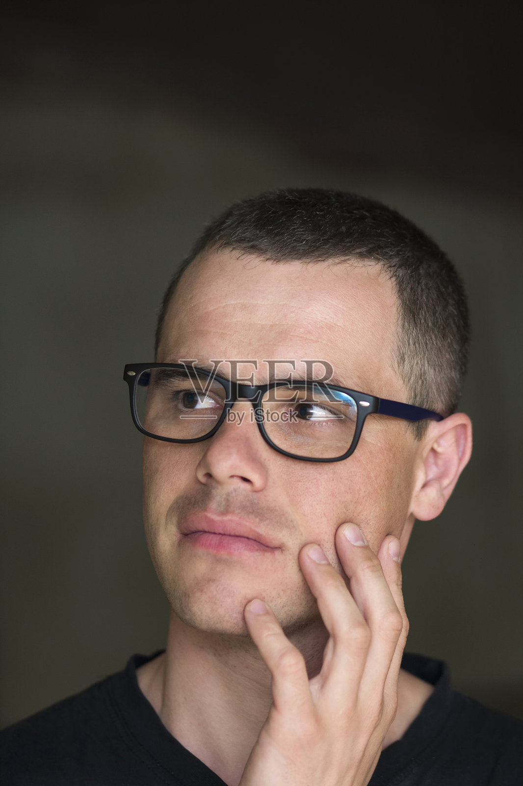 年轻英俊的肖像，严肃的黑发自信的成功知识分子戴着眼镜，闪亮的黑眼睛注视着黑暗的背景上的空间。照片摄影图片