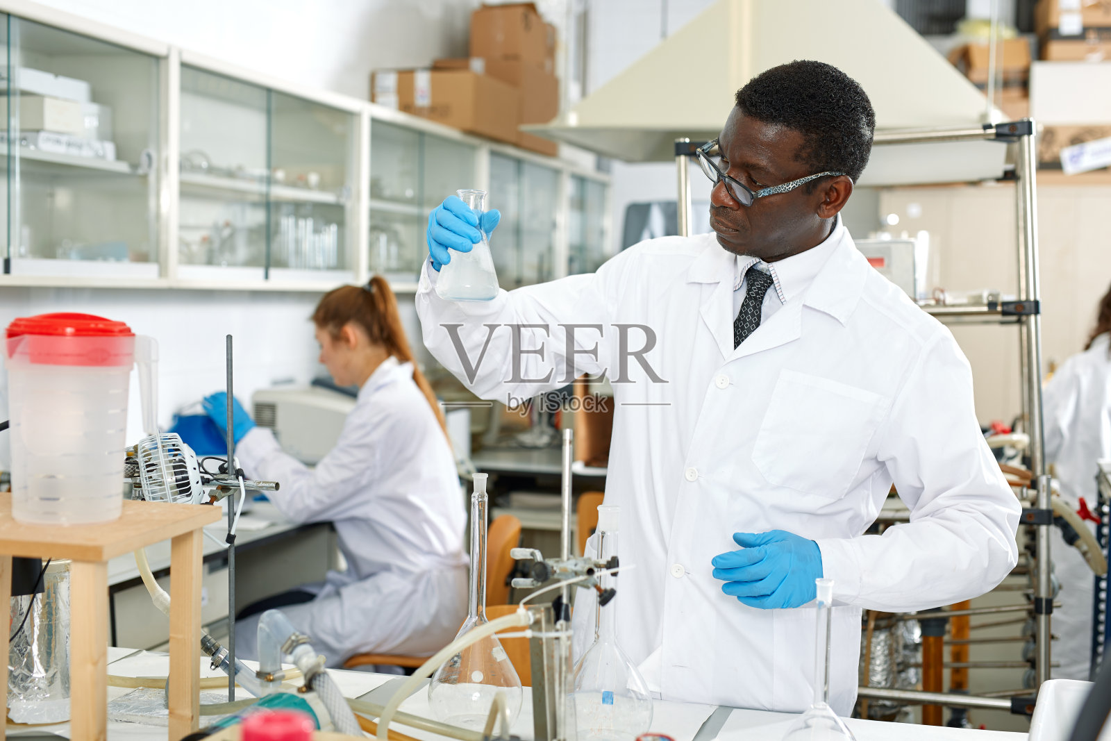 实验室里的专业科学家戴着眼镜，用试剂和试管工作照片摄影图片
