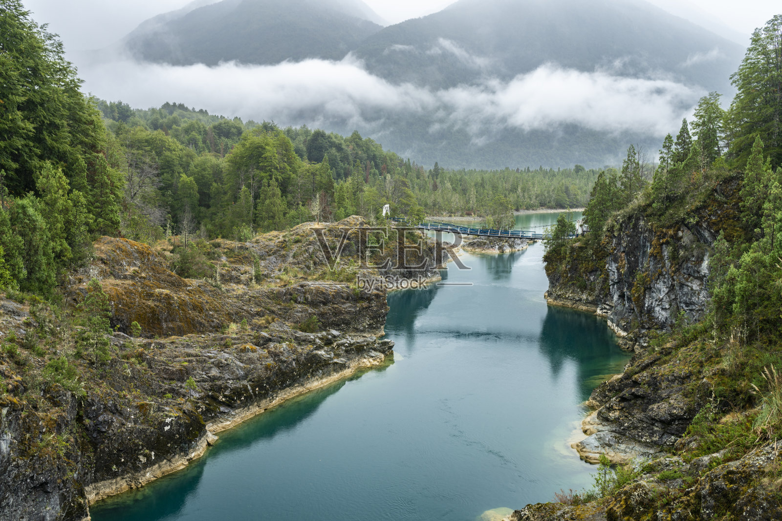 智利巴塔哥尼亚北部令人敬畏的吊桥，Puelo河在令人敬畏的田园诗般的自然环境下，在引人注目的天空下，以其绿松石般的水域环绕狭窄的峡谷照片摄影图片