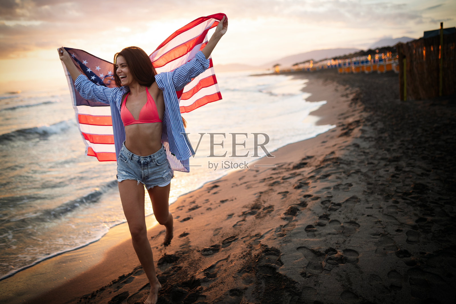 快乐的女人在海滩上跑步，庆祝独立日，享受美国的自由照片摄影图片
