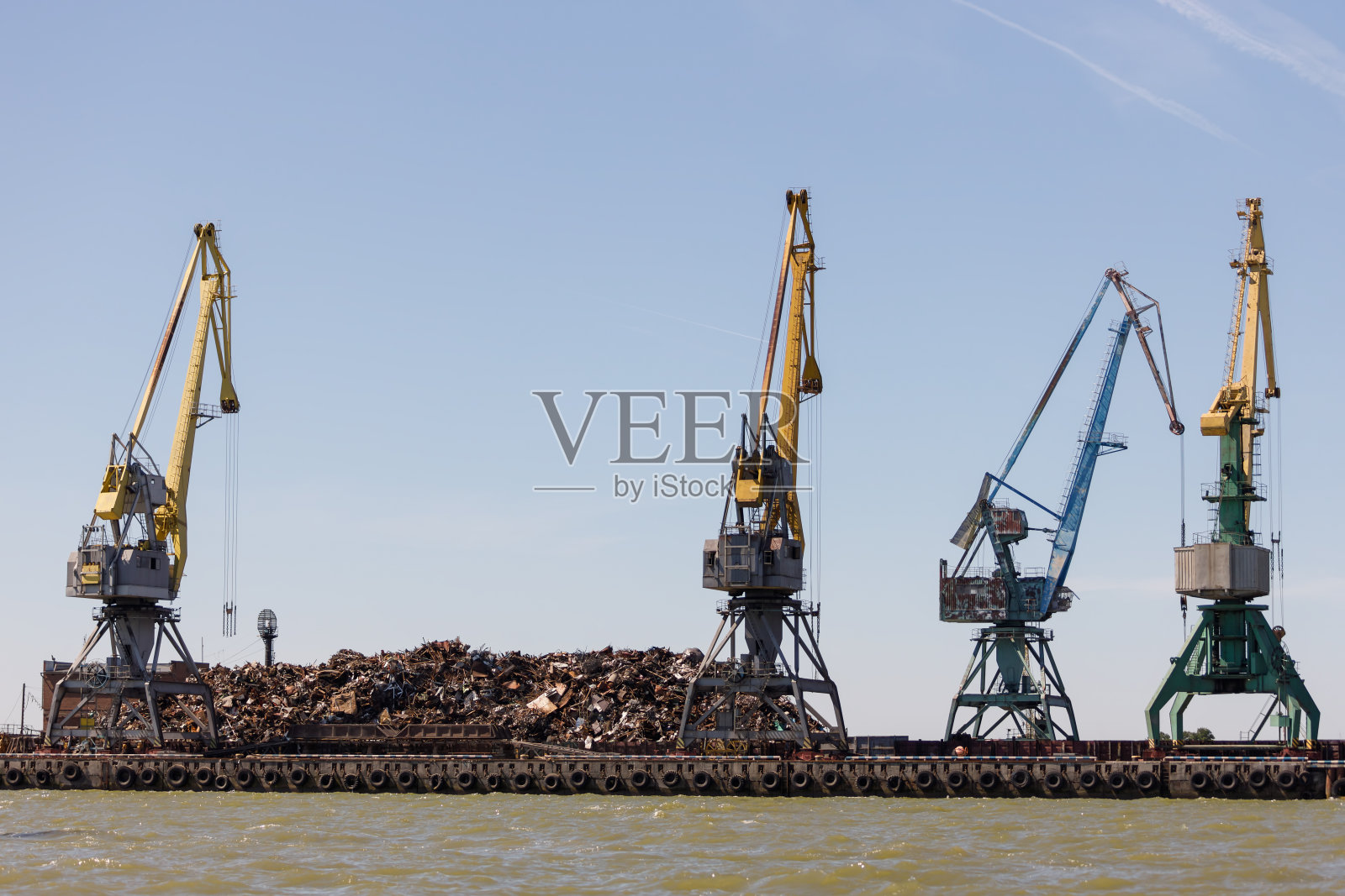 码头上有一大堆金属废料，准备用起重机装载到船上照片摄影图片