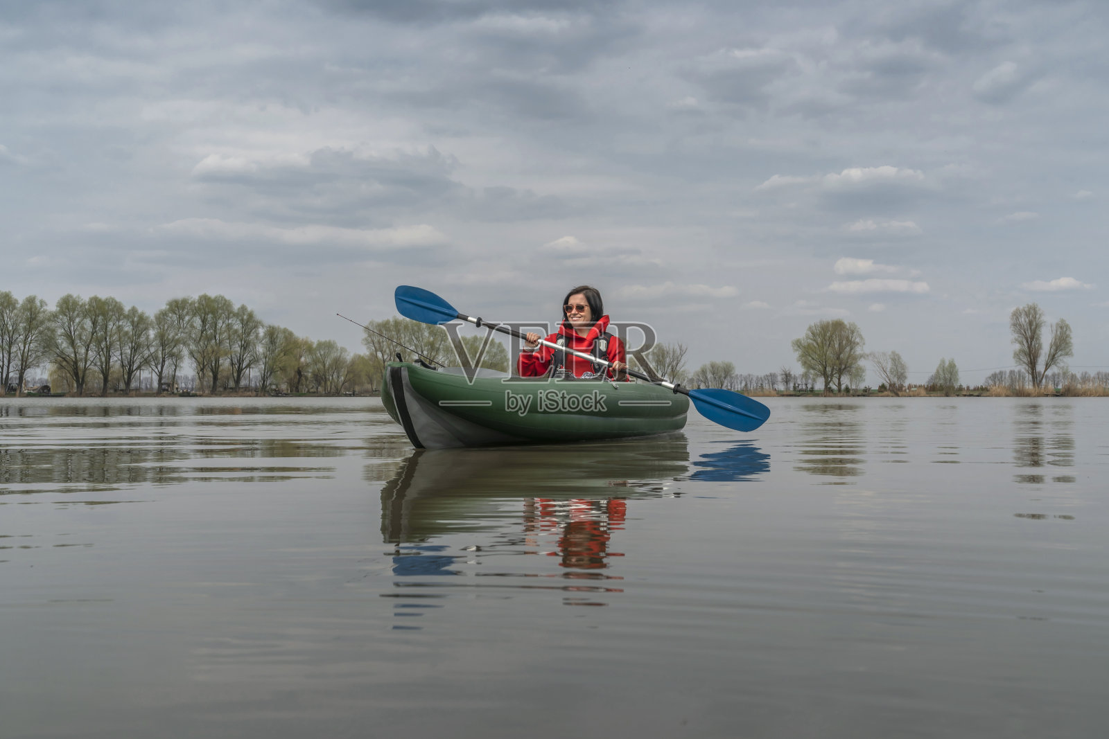 在湖中划皮艇钓鱼。带着渔具坐在充气船上的渔民。照片摄影图片