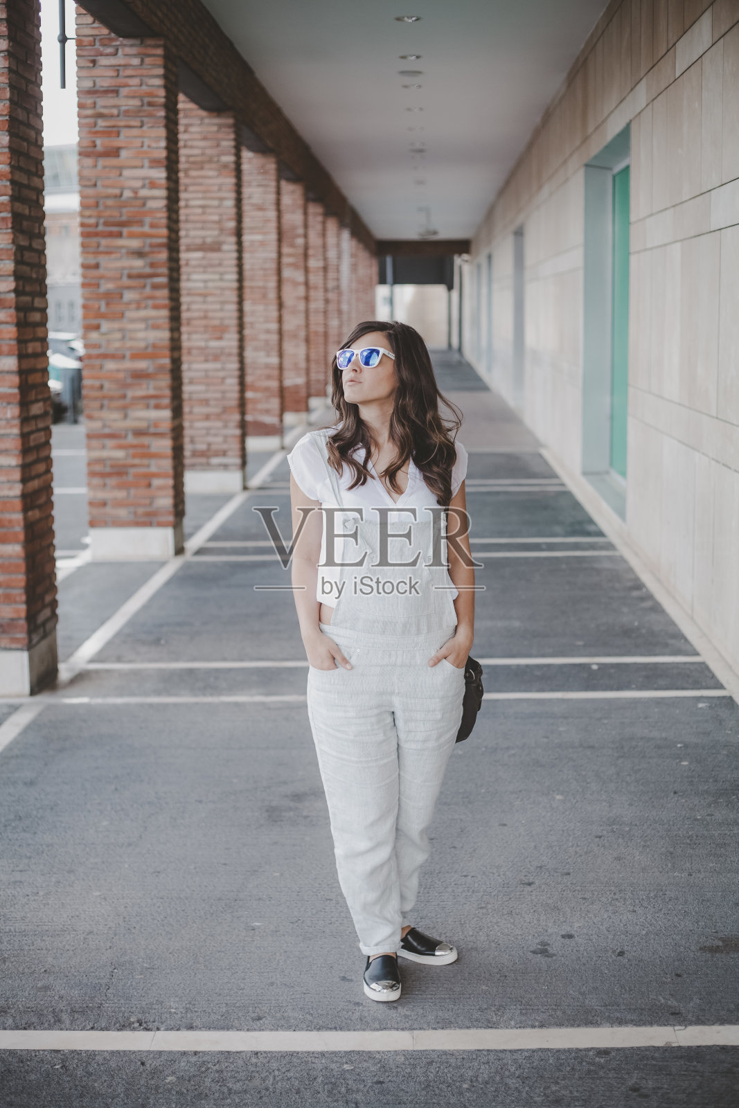 穿着工作服戴着墨镜的女人在画廊里摆姿势照片摄影图片