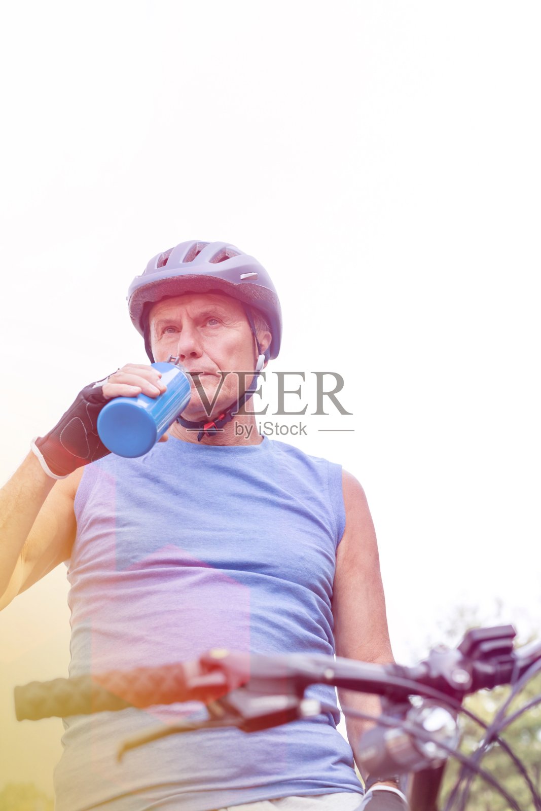 有决心的骑手在公园喝水，对着天空照片摄影图片