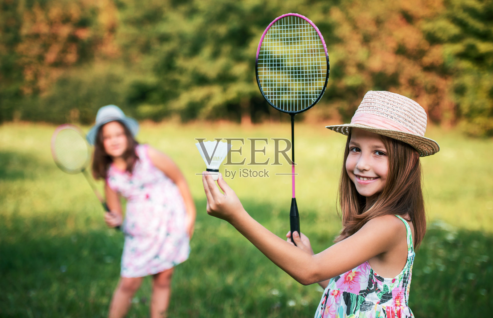 童年时间。两个小女孩在公园里打羽毛球照片摄影图片