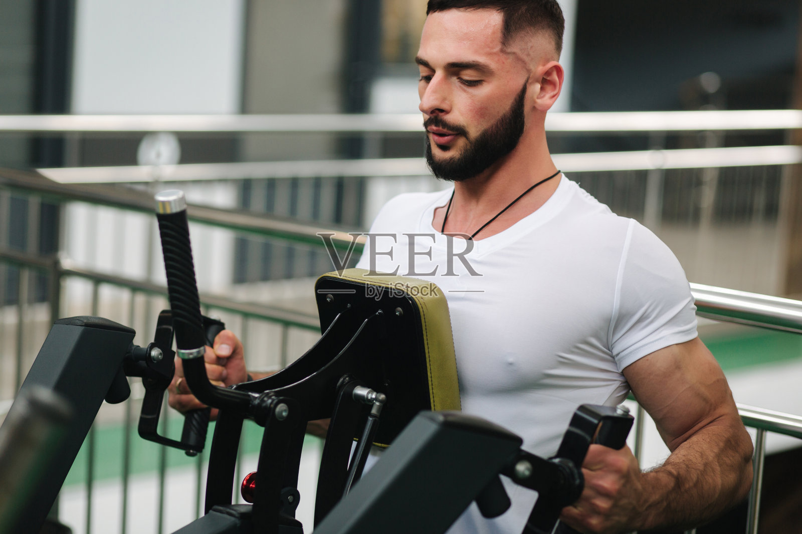 一个年轻的运动员在体育馆里训练。健美运动员训练背部肌肉照片摄影图片