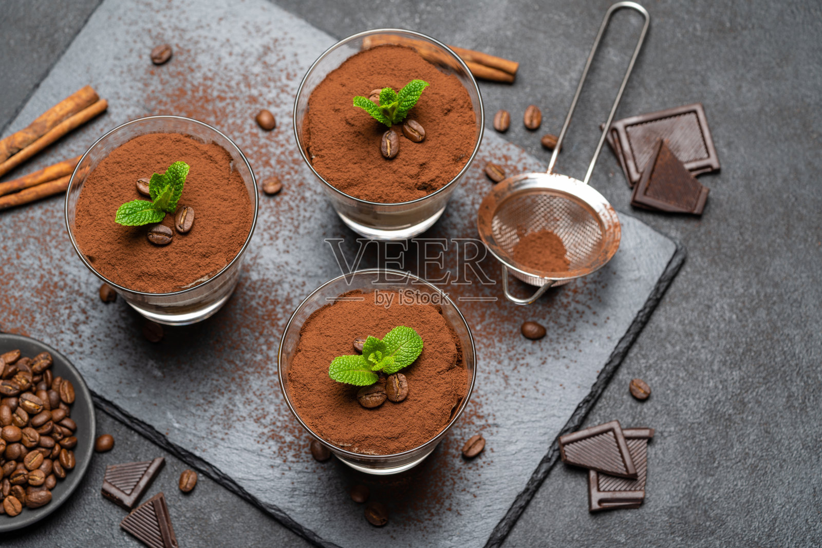 经典的提拉米苏甜点在玻璃上的石头服务板上深色混凝土背景照片摄影图片