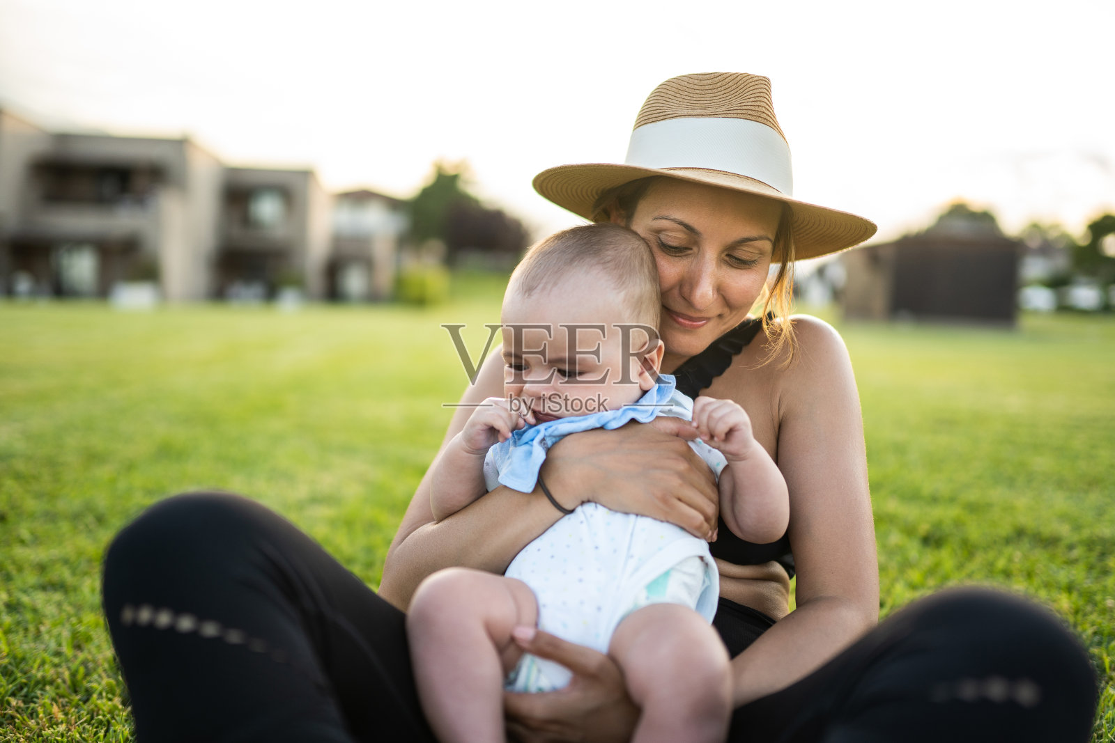 在一个阳光明媚的日子里，母亲和婴儿坐在草地上照片摄影图片