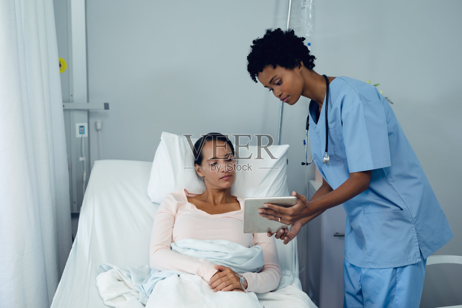 女医生在病房用平板电脑向女病人展示医疗报告照片摄影图片
