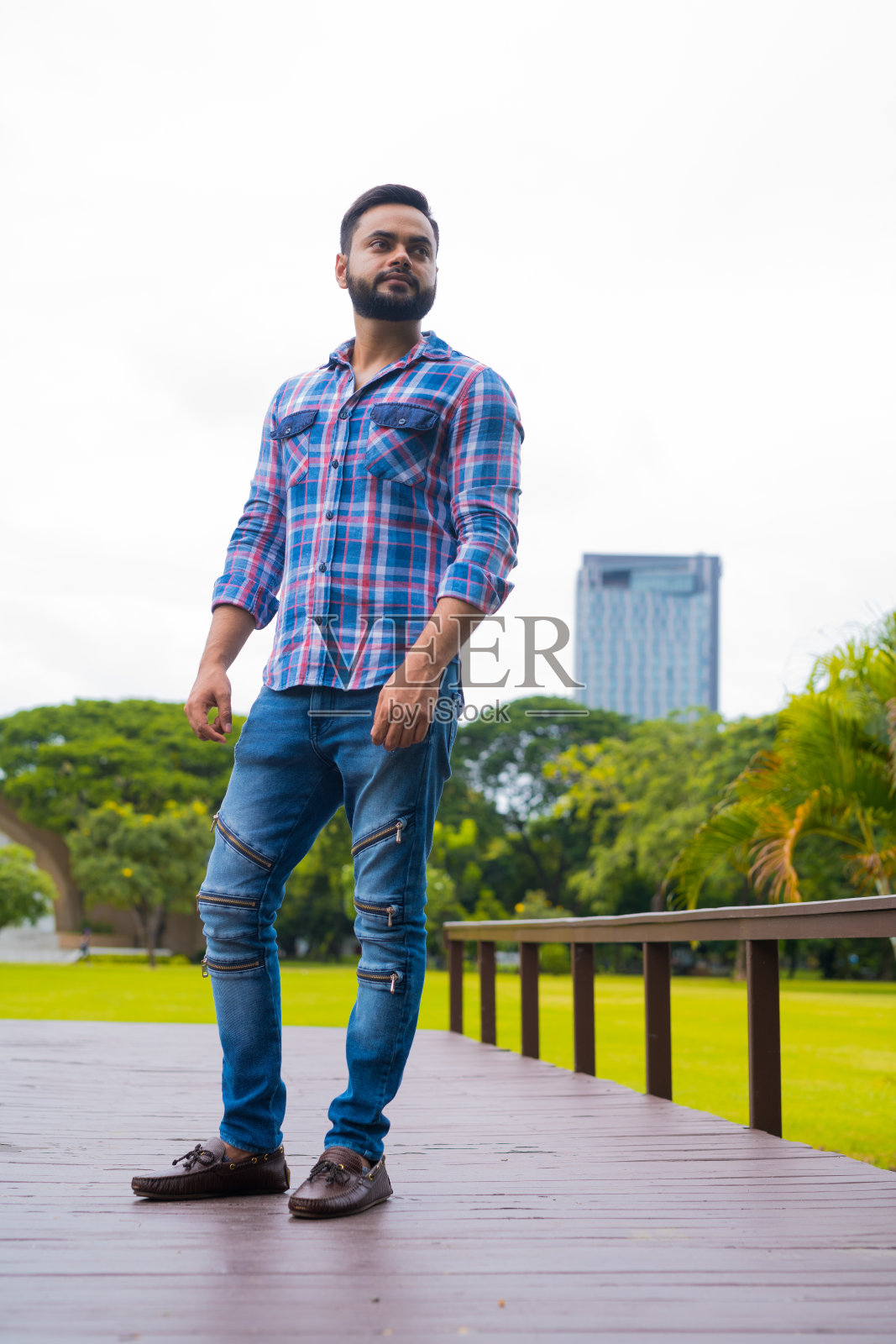 年轻英俊的印度男人站在公园里思考照片摄影图片