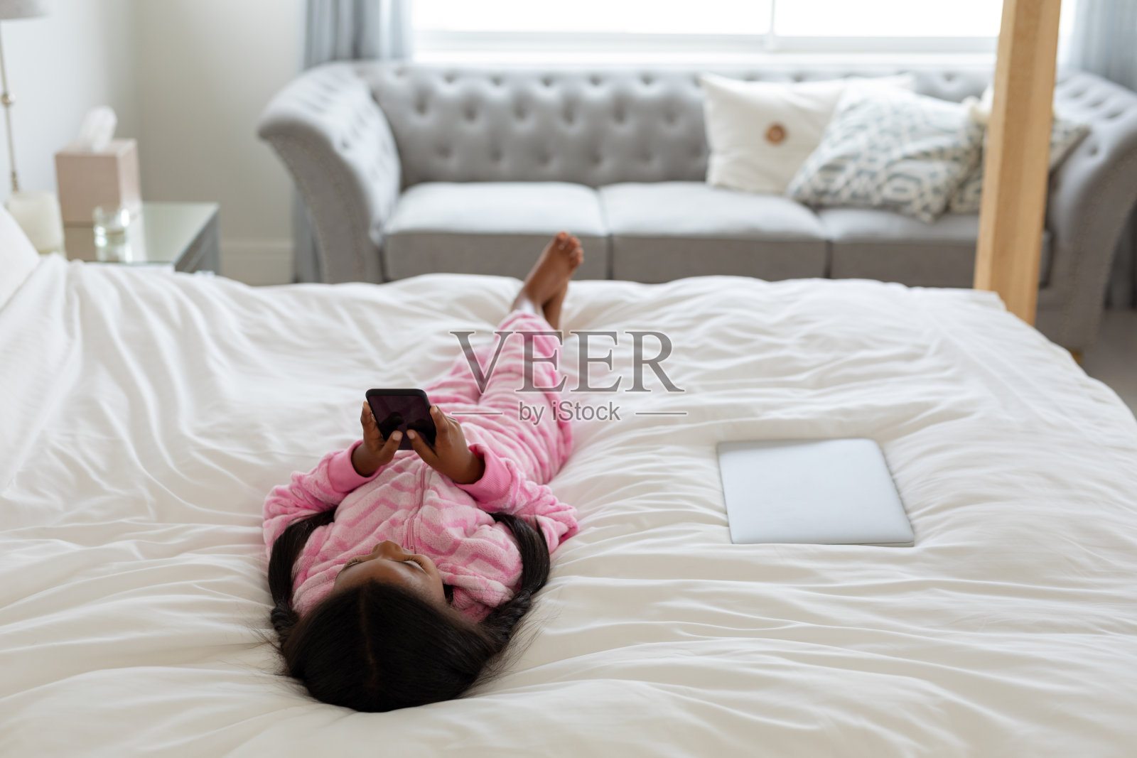 女孩躺在床上玩手机照片摄影图片