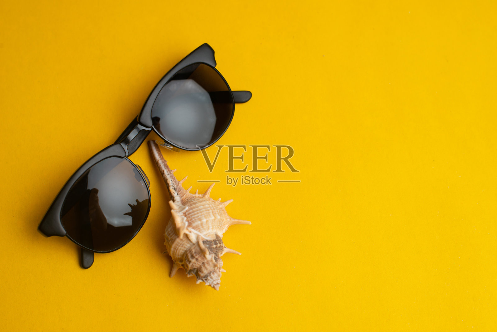 夏季饰品，贝壳和太阳眼镜在黄色的背景。夏天的概念。照片摄影图片