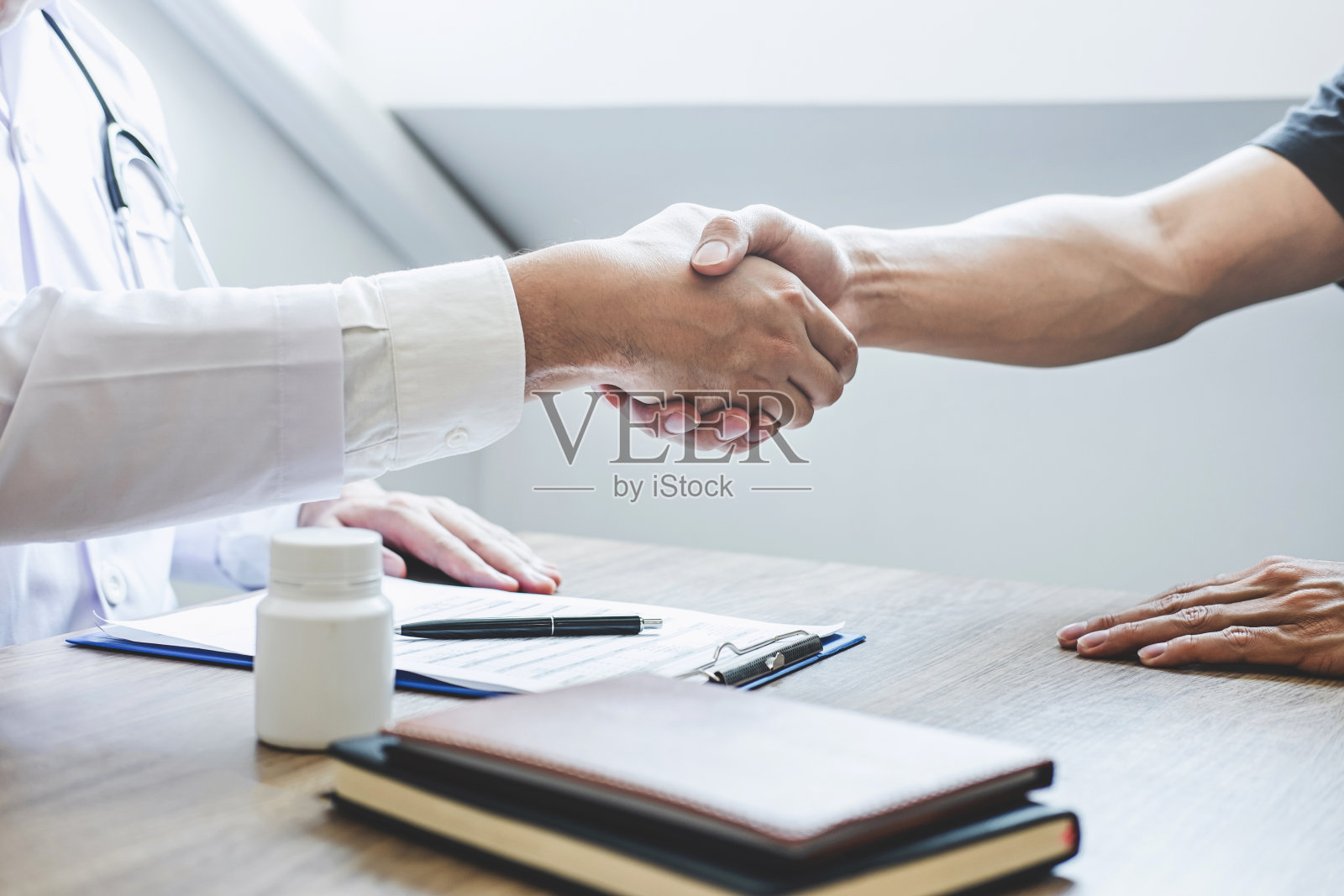 医生在推荐治疗后与患者握手祝贺，同时讨论解释他的症状，并建议诊断健康、保健和援助的概念照片摄影图片