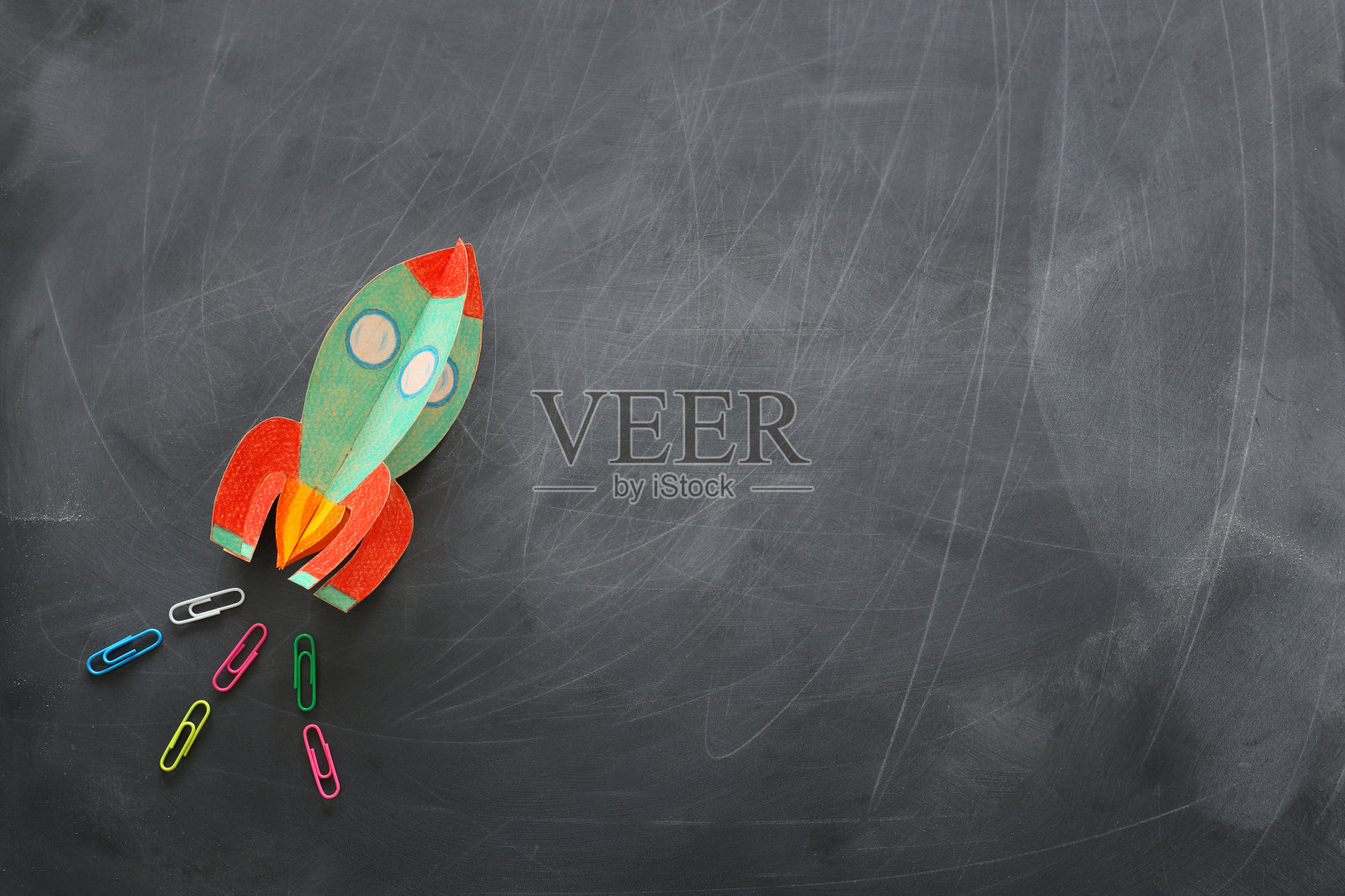 教育。回到学校的概念。火箭从纸上剪下来，涂在黑板背景上。俯视图，平放照片摄影图片