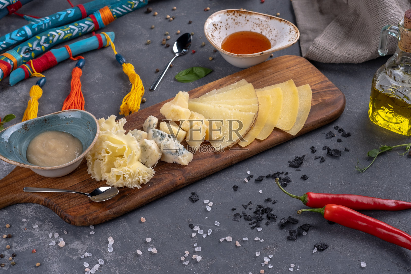 不同的奶酪切片放在配着调味汁的木盘子里照片摄影图片