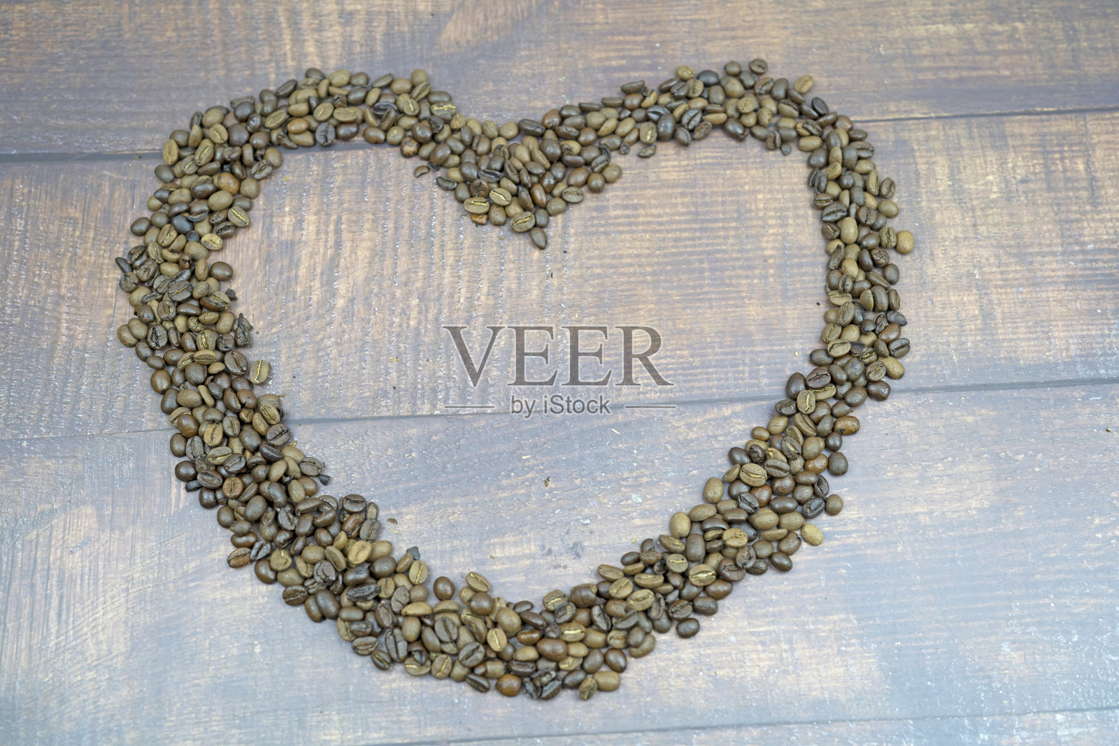 在木地板上放置烤咖啡豆的心形，作为背景和贺卡或明信片照片摄影图片