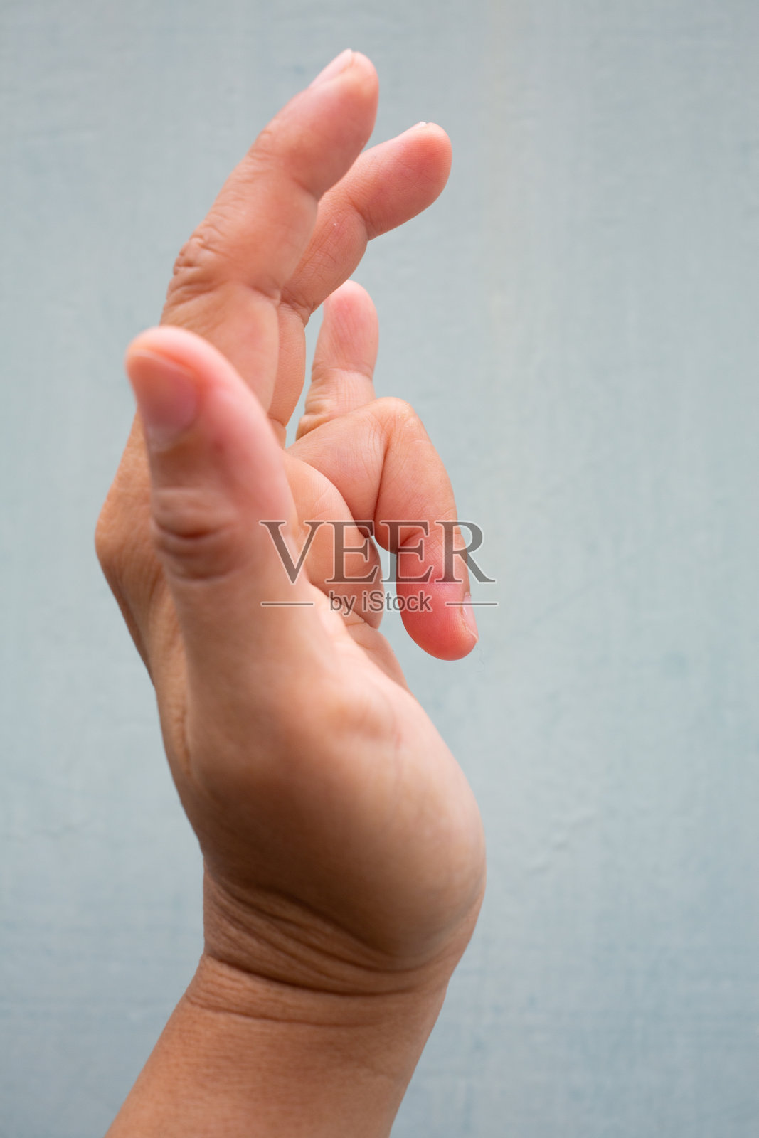扳机指锁在女性左手无名指上，疼痛，蓝灰背景，近距离微距拍摄，办公室综合症，保健理念照片摄影图片