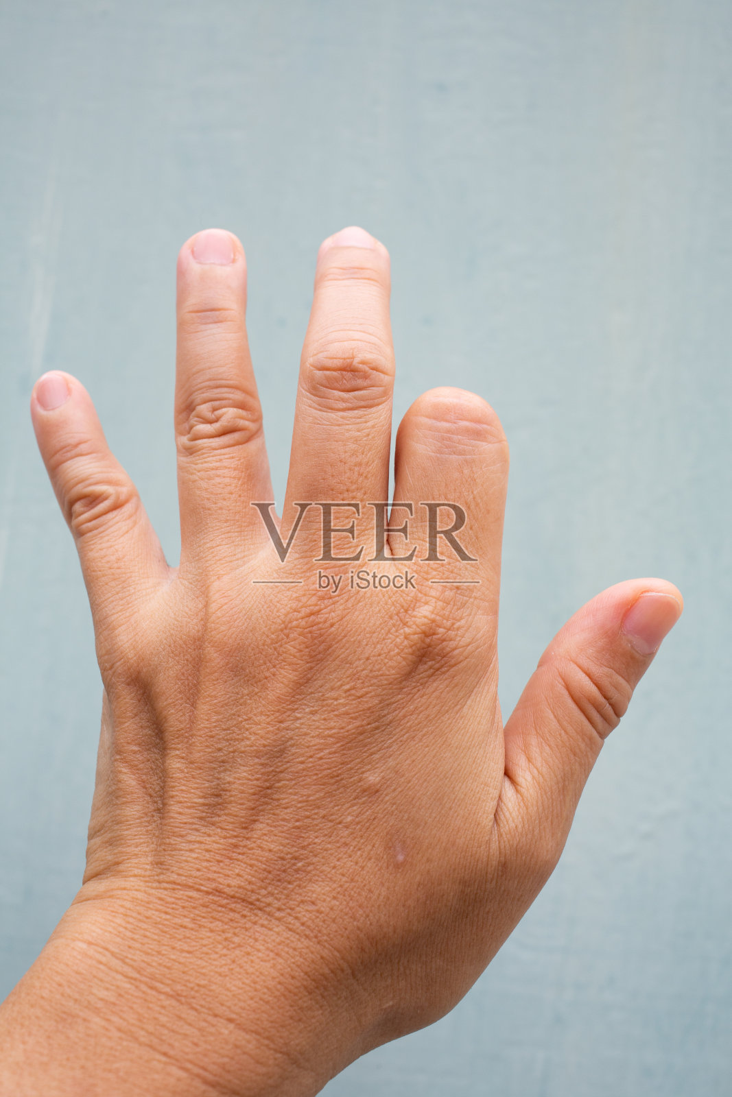 扳机指锁在女性左手后侧食指上，疼痛，蓝灰背景，近距离微距拍摄，办公室综合症，保健理念照片摄影图片