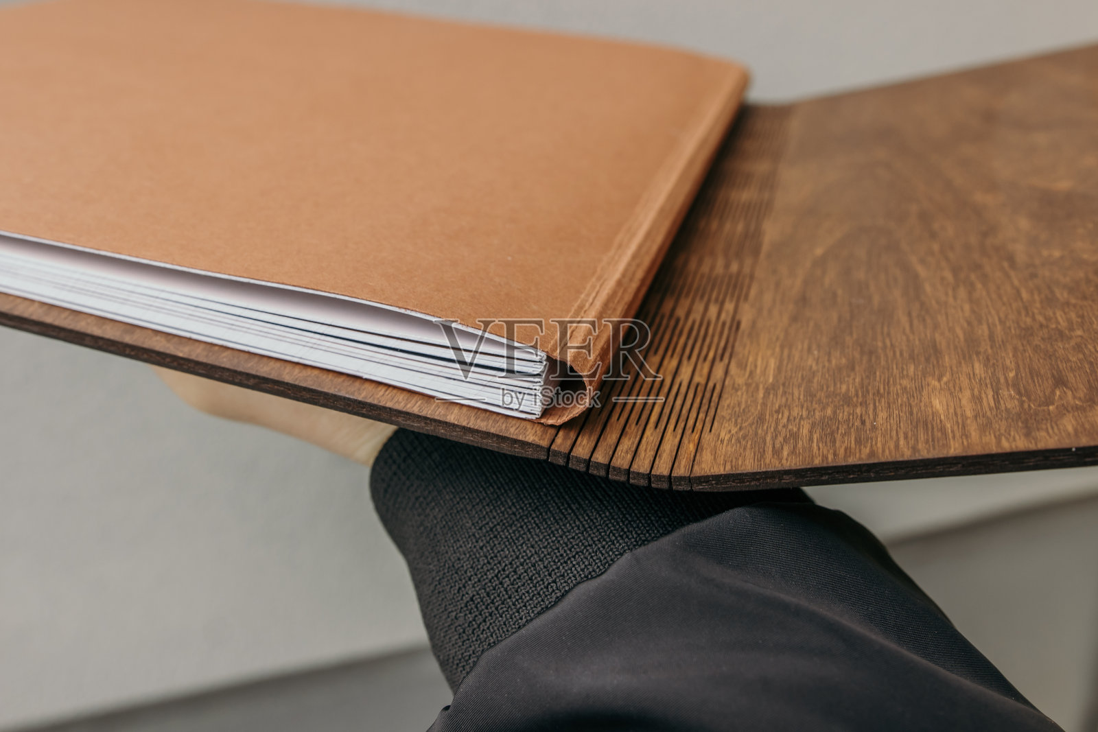 打开木制封面的相册。胶合板封面的笔记本。木制封面的婚纱照。手里拿着婚礼相册。照片摄影图片