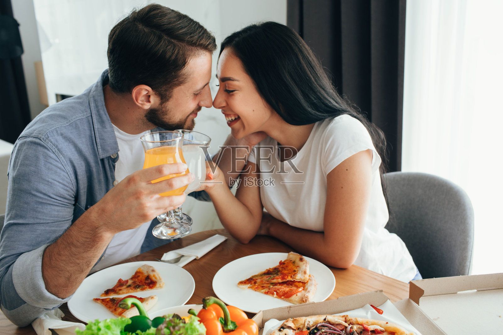 幸福的情侣接吻，在家吃披萨晚餐。在家里度过的好时光照片摄影图片