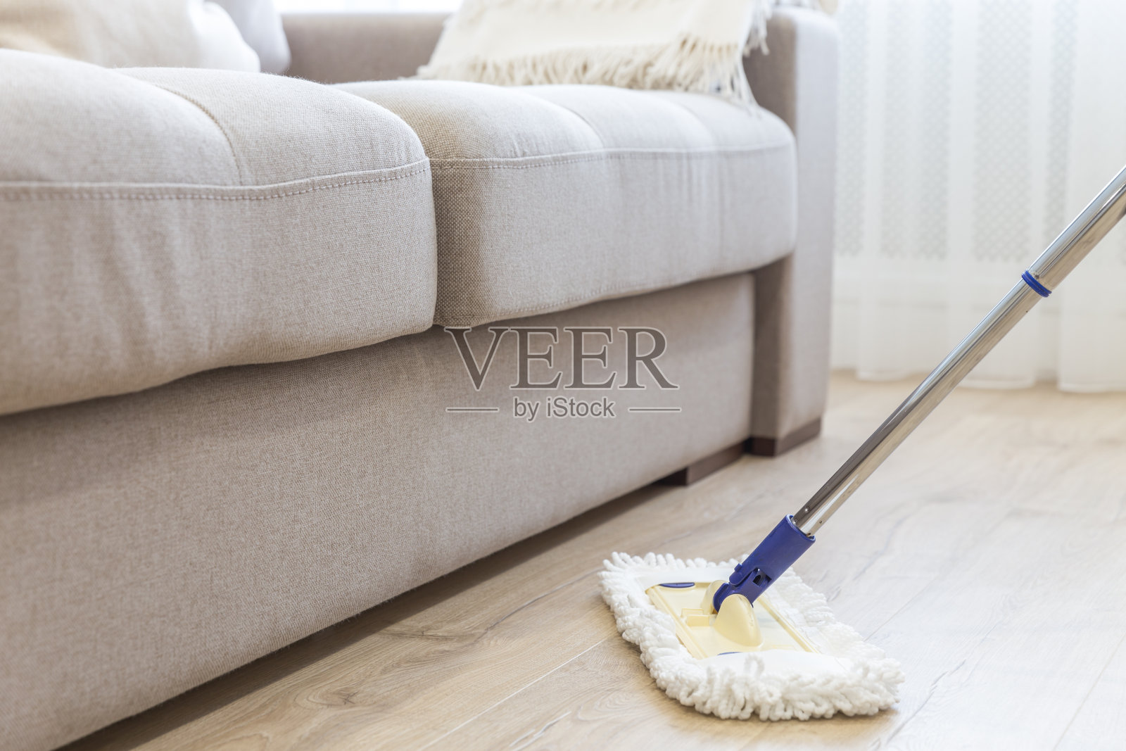 用白色拖把擦拭沙发旁的地板照片摄影图片