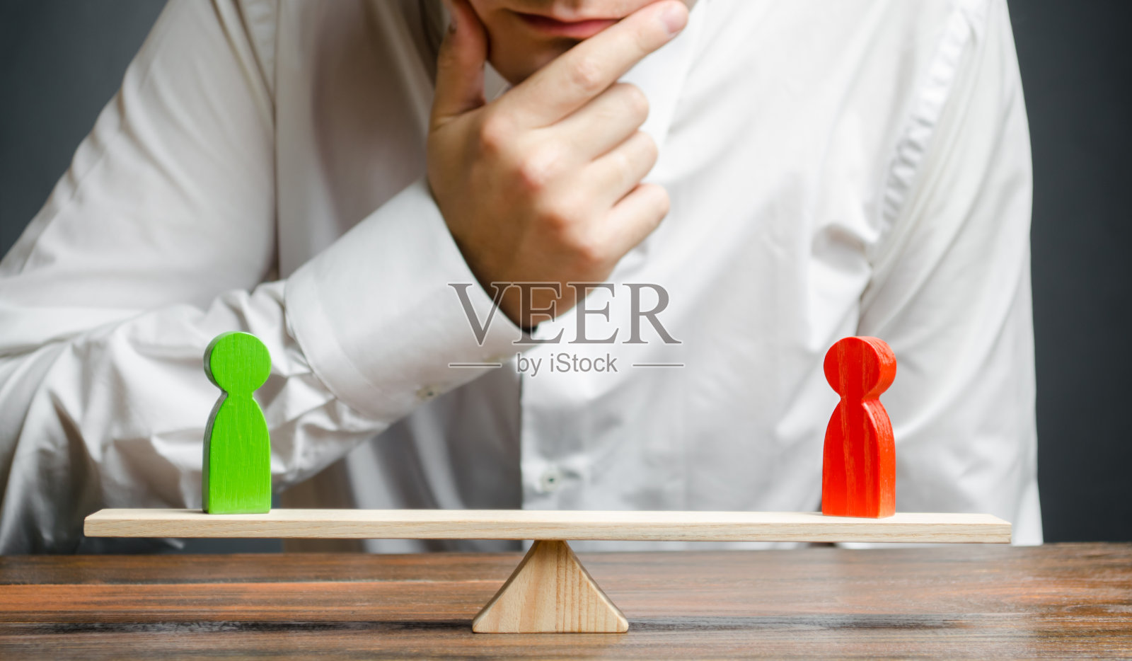 男人用手托着下巴看着鳞片上的红色和绿色的图案。加权的决定。解决冲突的概念和在争端中寻求妥协。照片摄影图片