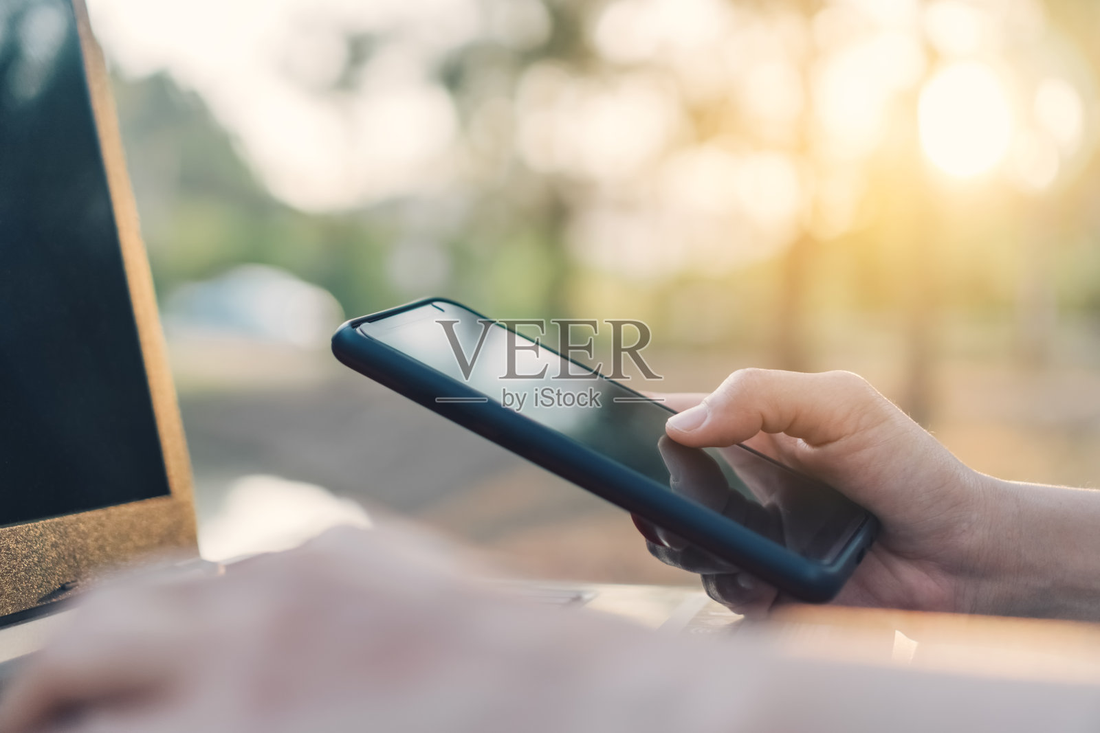 女人用智能手机和笔记本电脑在户外自然公园和日落天空与散景光抽象背景。技术业务和自由职业的工作理念。复古色调过滤效果色彩风格。照片摄影图片