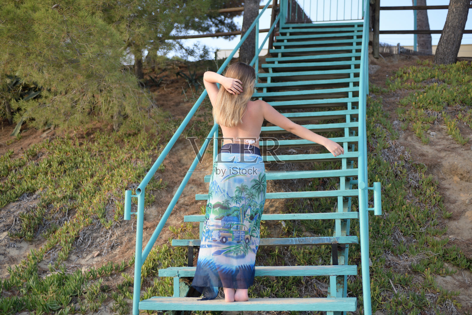 金发女孩在楼梯上对着镜头跳着舞，然后放下手臂照片摄影图片