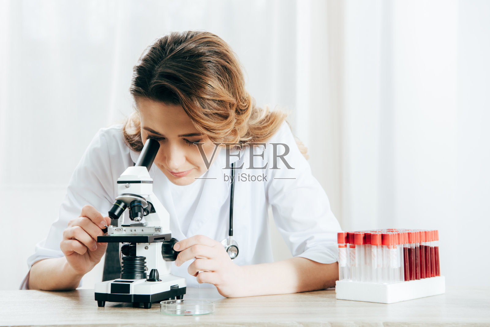 身穿白大褂的医生在临床中使用显微镜照片摄影图片