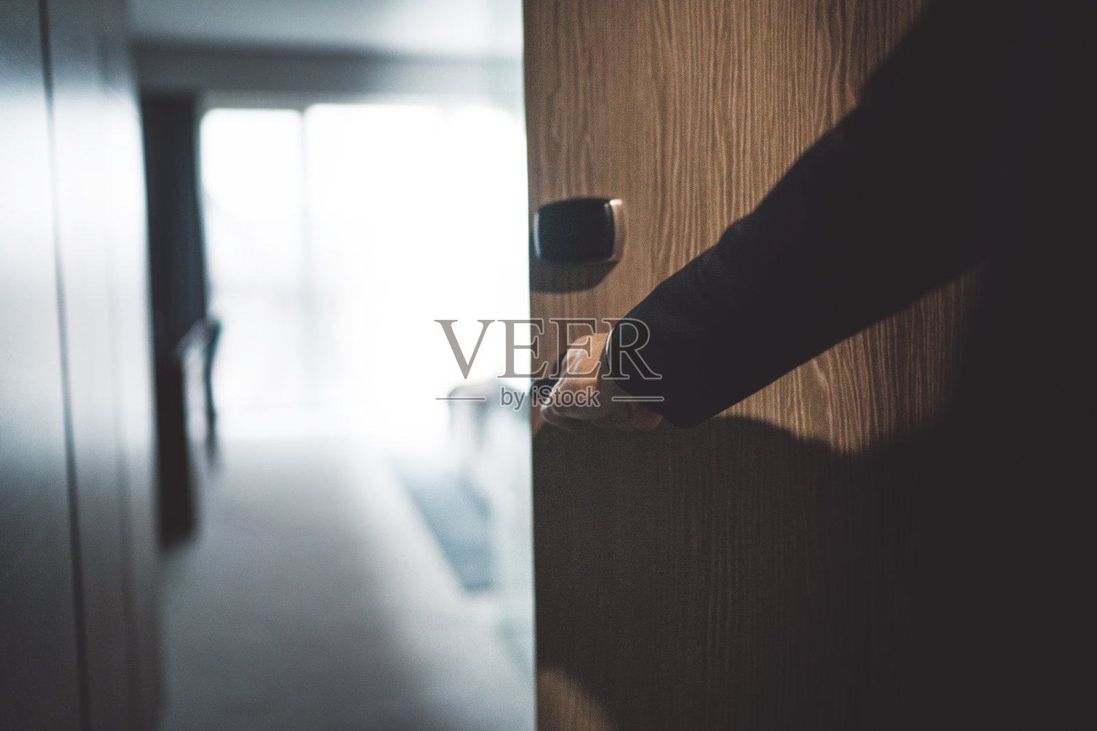 一个穿西装的男人打开他的酒店房间的门照片摄影图片