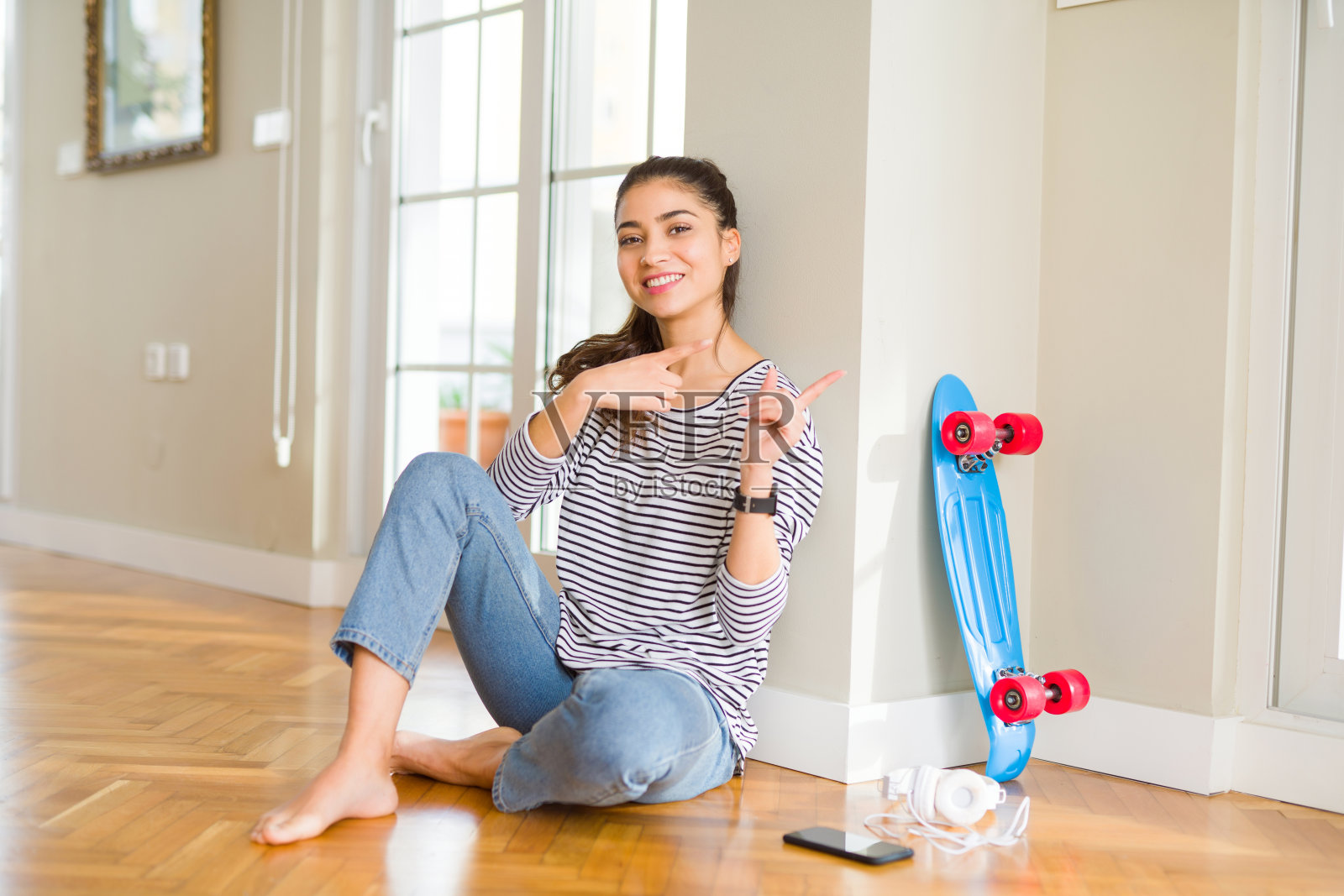 年轻女人坐在地板上玩滑板照片摄影图片