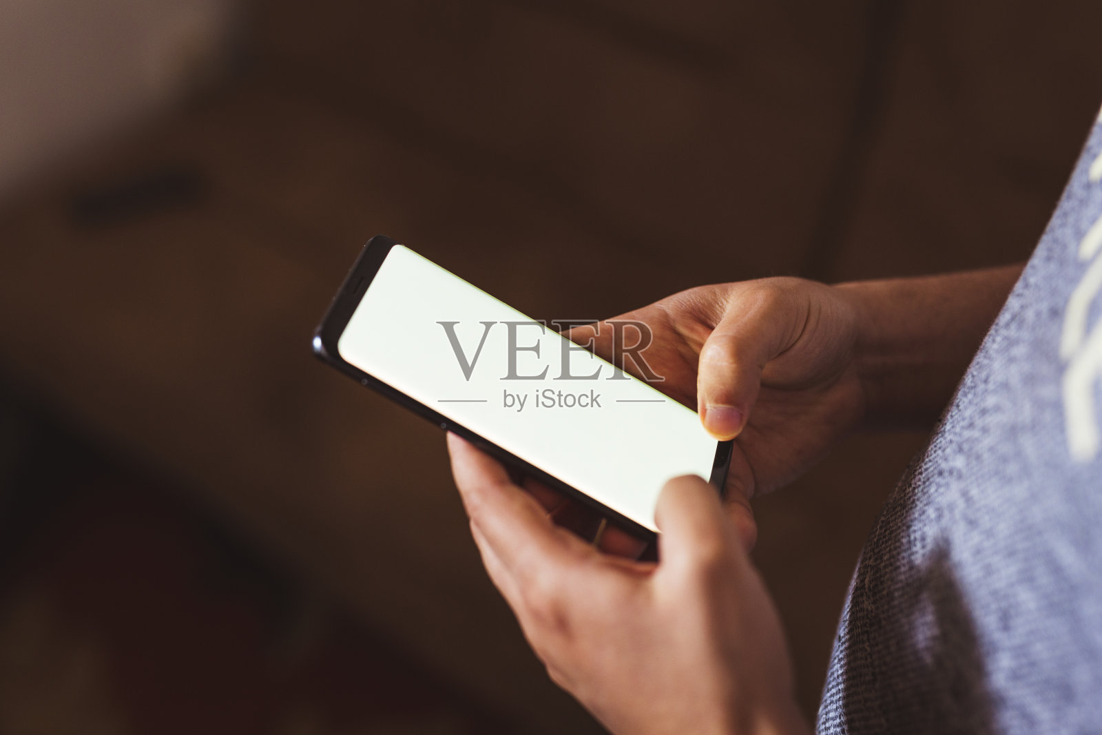 一个男人在咖啡店里拿着手机。人使用智能手机。空白屏幕与文本或内容的复制空间照片摄影图片