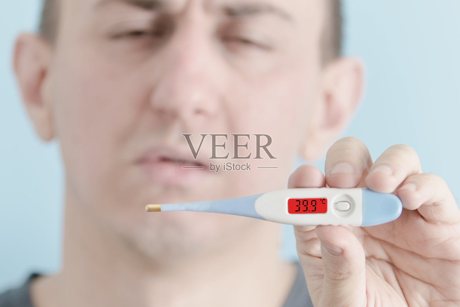 手里拿着温度计的男人。体温升高照片摄影图片
