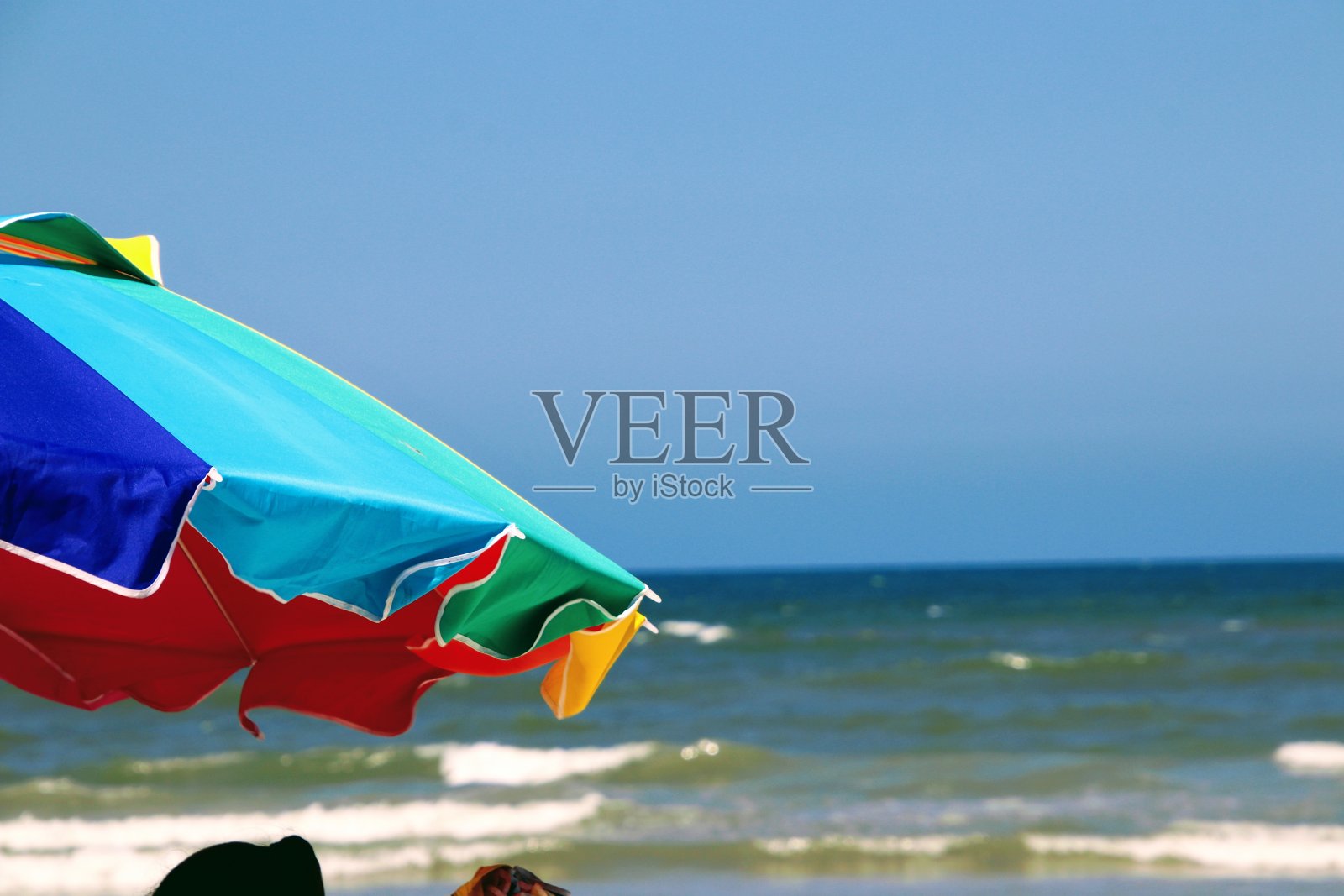 五颜六色的沙滩伞在晴朗多风的蓝天。照片摄影图片