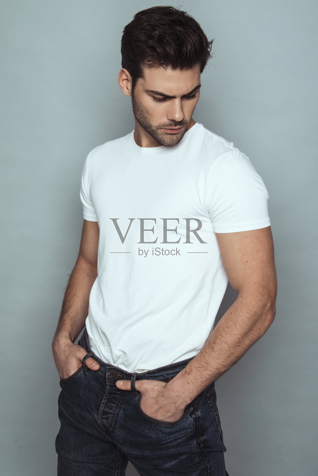 肌肉强壮美丽的剥离男性模特在牛仔蓝色牛仔裤和白色t恤灰色孤立的字体背景照片摄影图片