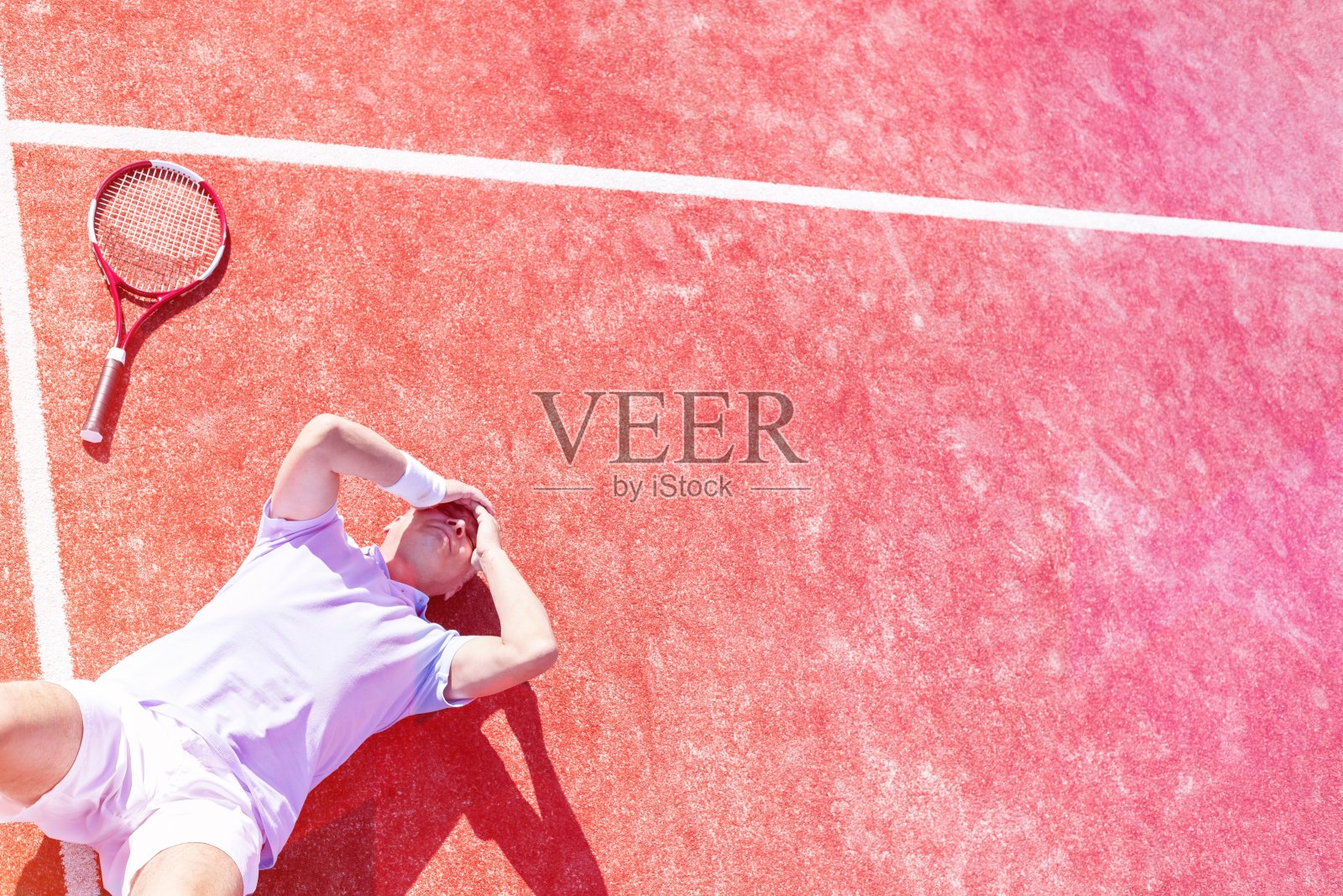 高角度的失望的成熟男子与头在手，而躺在网球拍在球场在夏天照片摄影图片