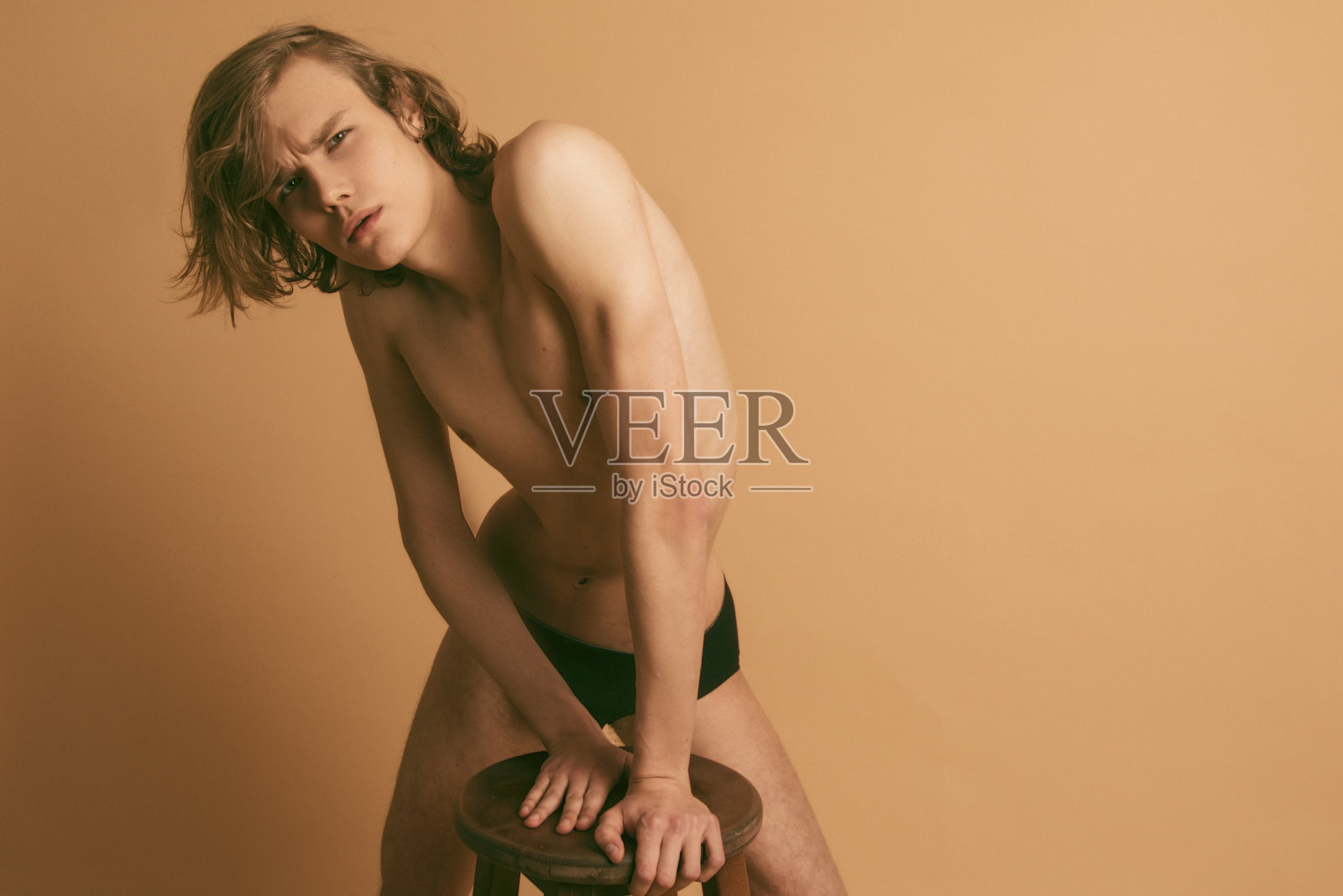 肌肉强壮美丽的脱衣男模特在黑色内衣上米色孤立的字体背景照片摄影图片