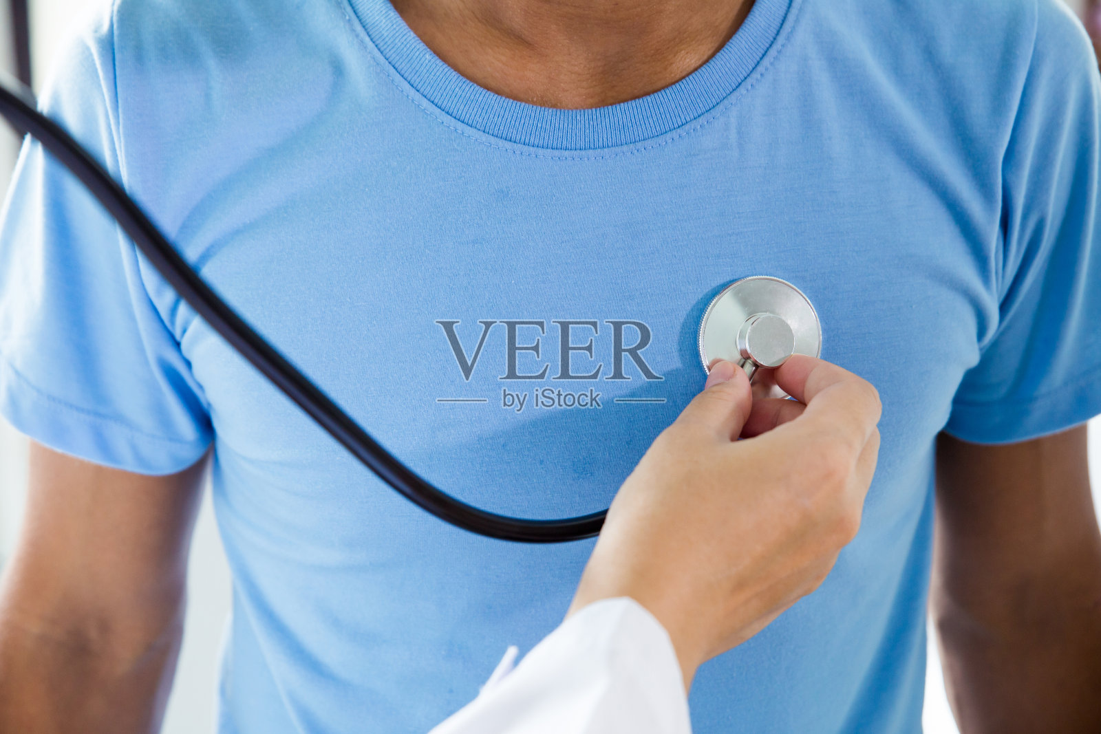 医学概念。医生正在用听诊器检查病人的胸部，听病人的心率照片摄影图片