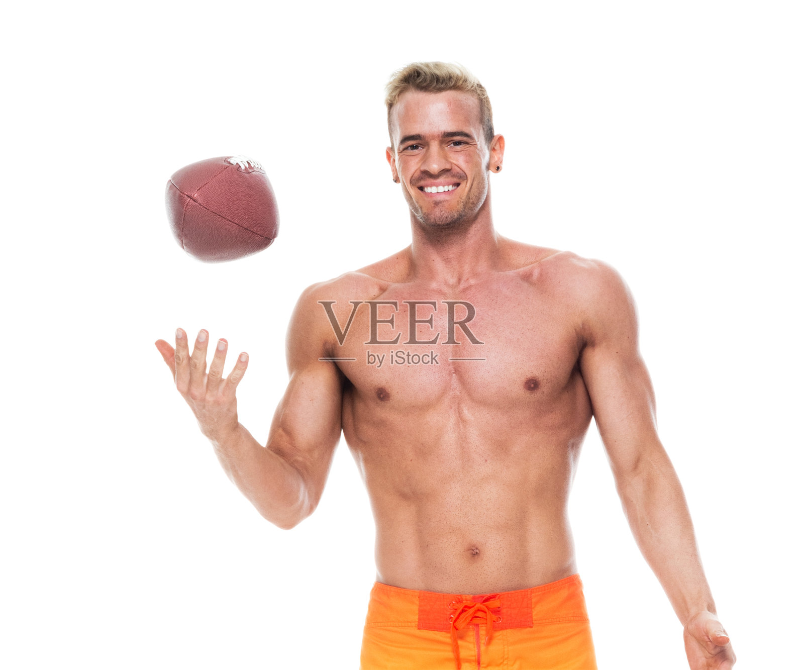 年轻英俊的男人拿着橄榄球，穿着滑板短裤照片摄影图片