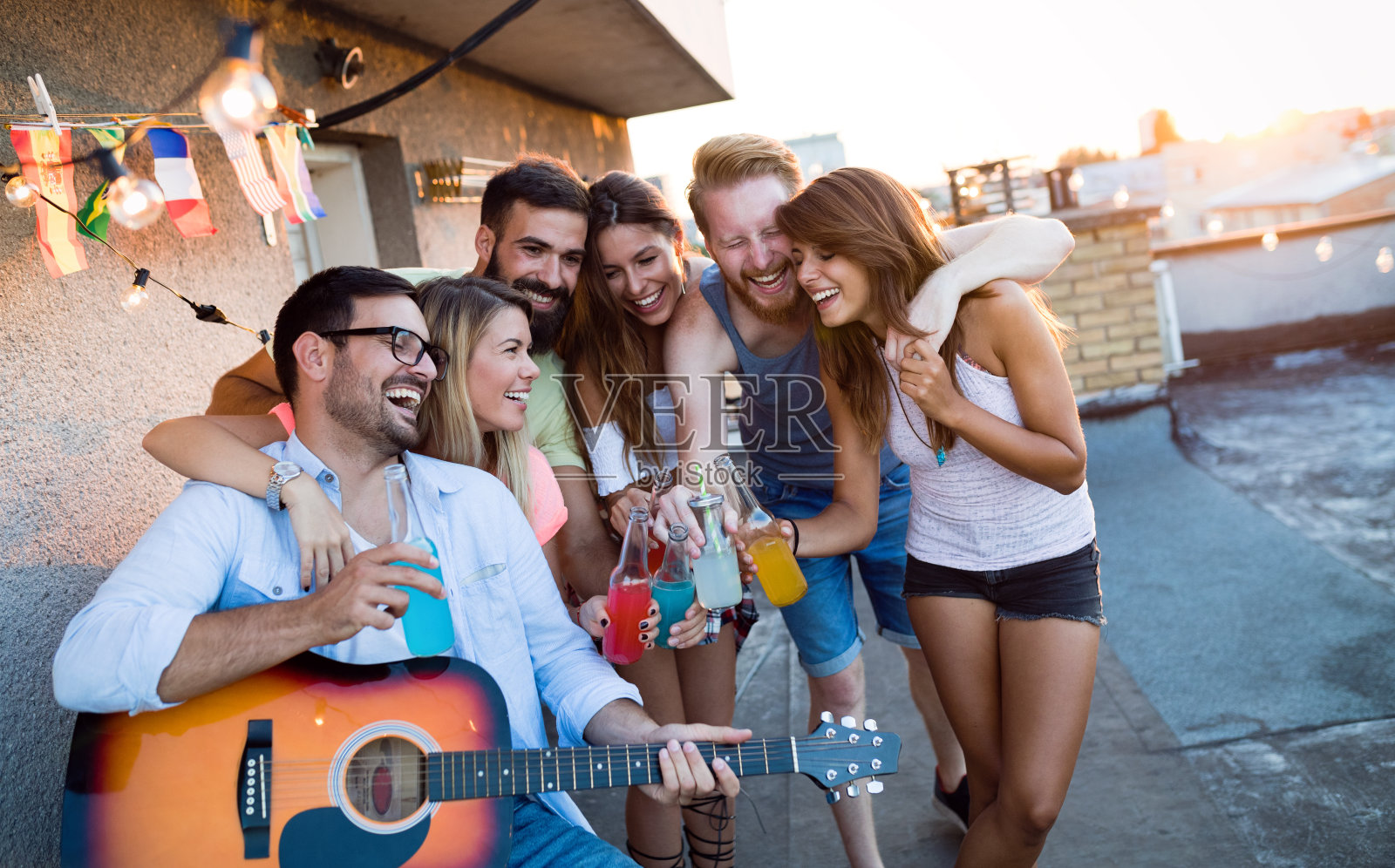 年轻的朋友们在一个屋顶派对上玩吉他，唱歌，跳舞和喝酒照片摄影图片