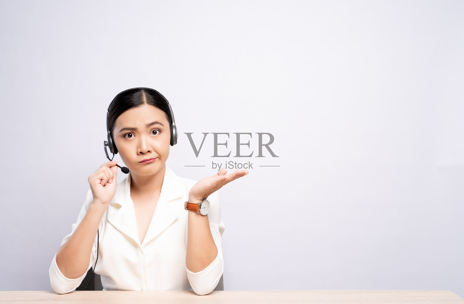 戴耳机的女操作员对白色背景感到困惑照片摄影图片